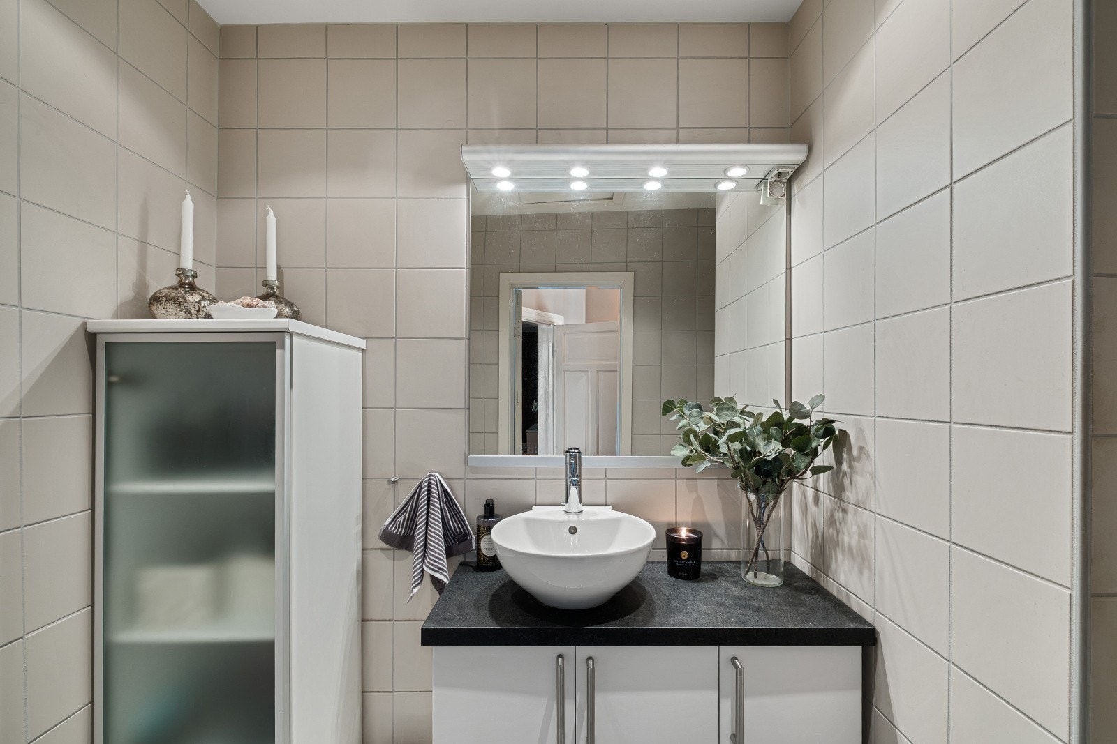 Badet er delikat og tidløst fra 2005, og er innredet med flislagte overflater og fremstår funksjonelt med dusjløsning, bollet servant på benkeplate og toalett Galleribilde
