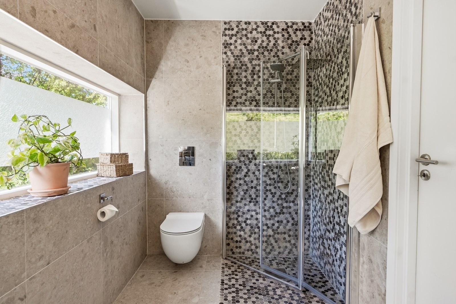 Dusjsonen har glassvegg og pene flisdetaljer. Badet fremstår moderne, praktisk og gjennomført. Galleribilde