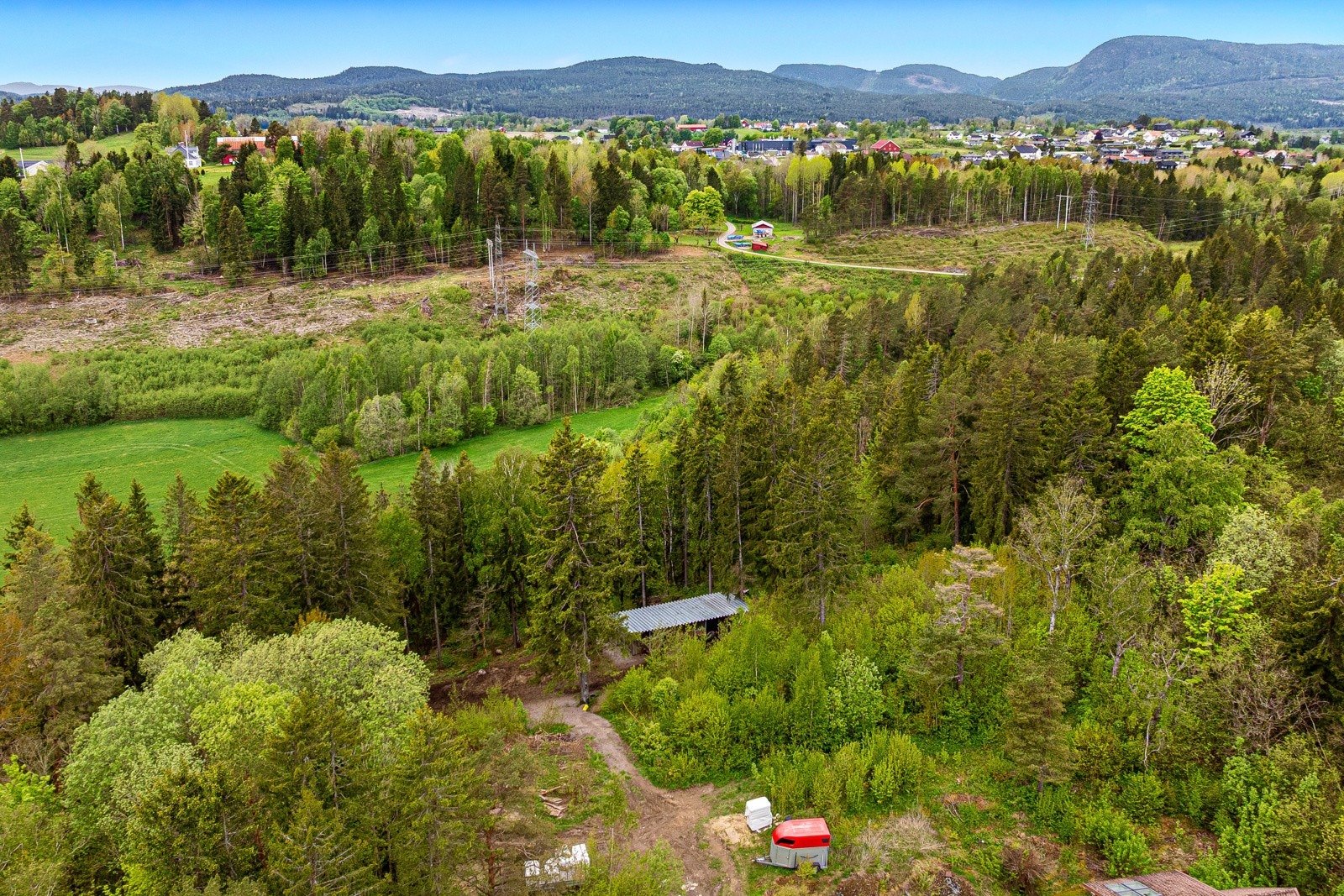 Del av skogteig på andre side av Holmsvegen 88, der nabo har bruksrett for hest (der man ser hestehenger og tekke) Galleribilde