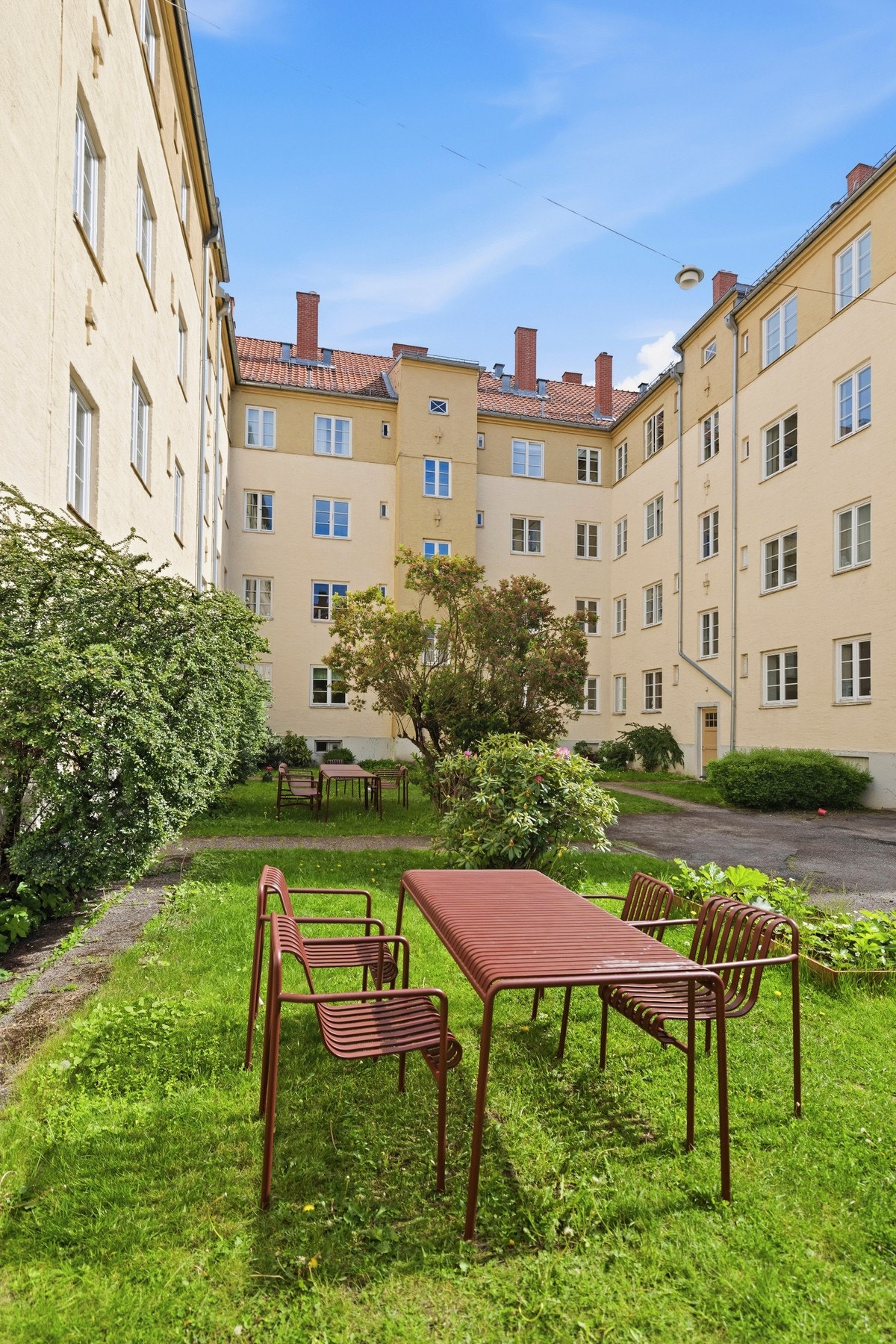 Stor og solrik felles bakgård med sittegrupper, grill, lekeapparater og grønnsakshage. Galleribilde