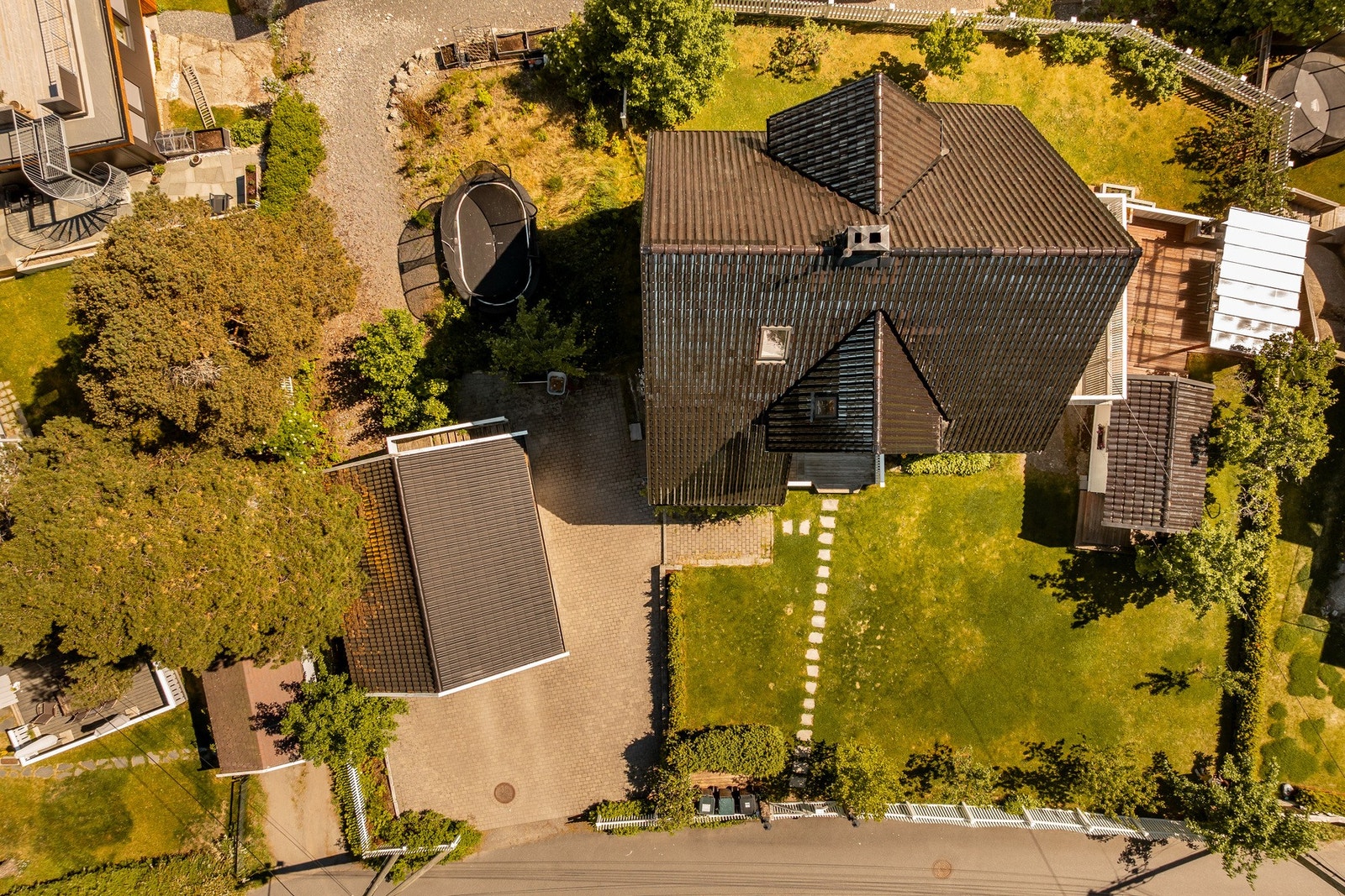 Tomten er opparbeidet med en steinsatt gårdsplass og en skjermet hage med fin beplantning og gressplen for lek. Galleribilde