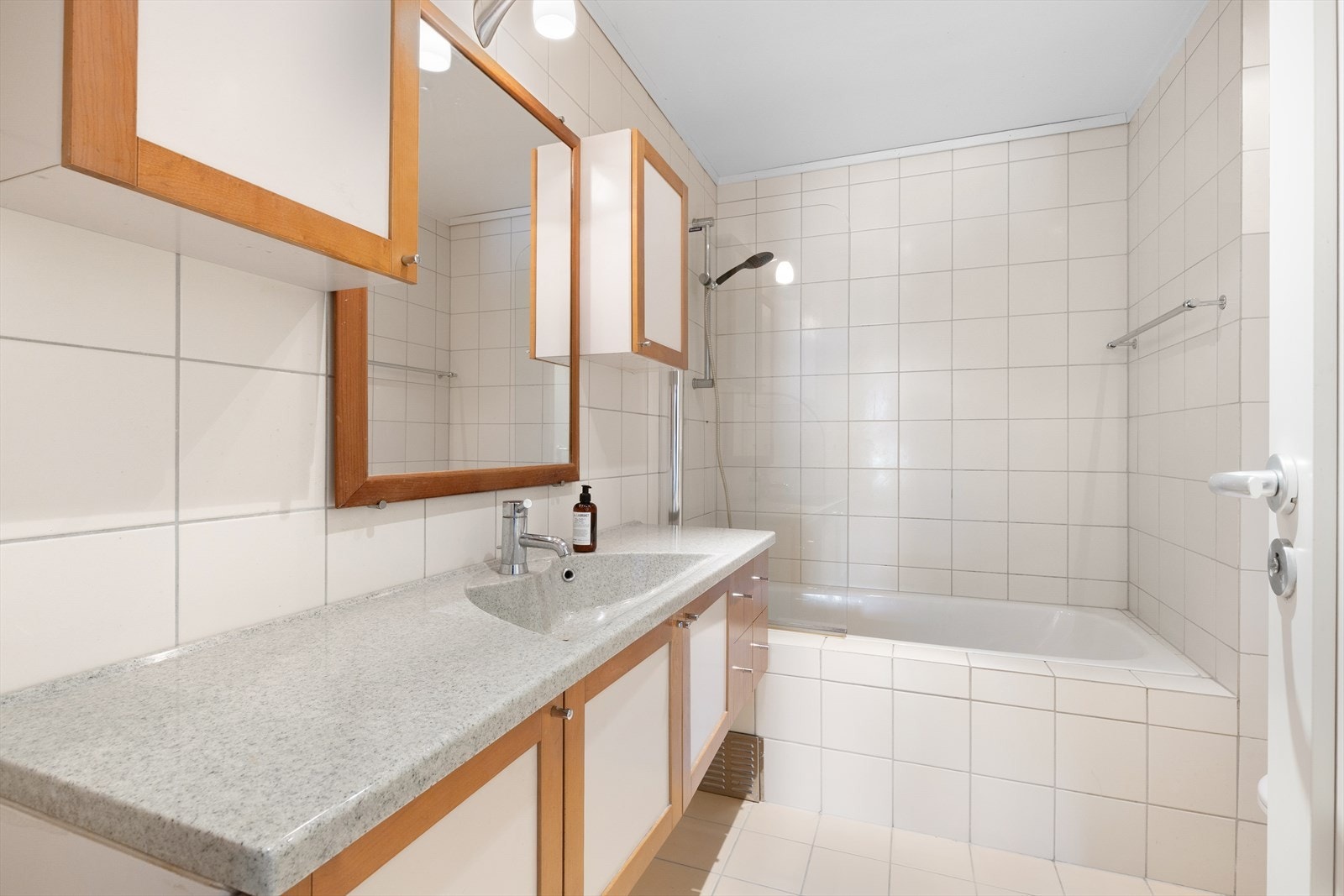 Pent bad med dusj/badekar, toalett, servantinnredning og overskap. Galleribilde