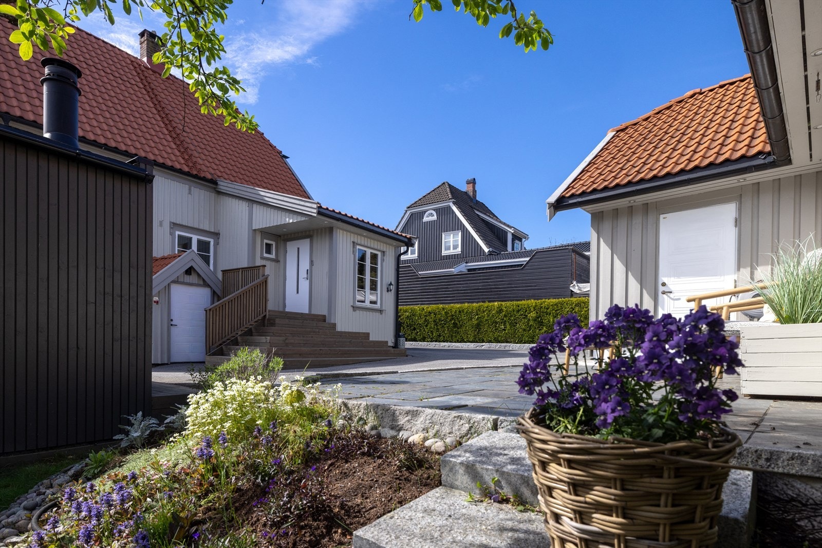 Asfaltert gårdsplass omgitt av hekker og tett gjerde mot veien - rolig og tilbaketrukket til tross for beliggenheten langs Onsøyveien. Galleribilde