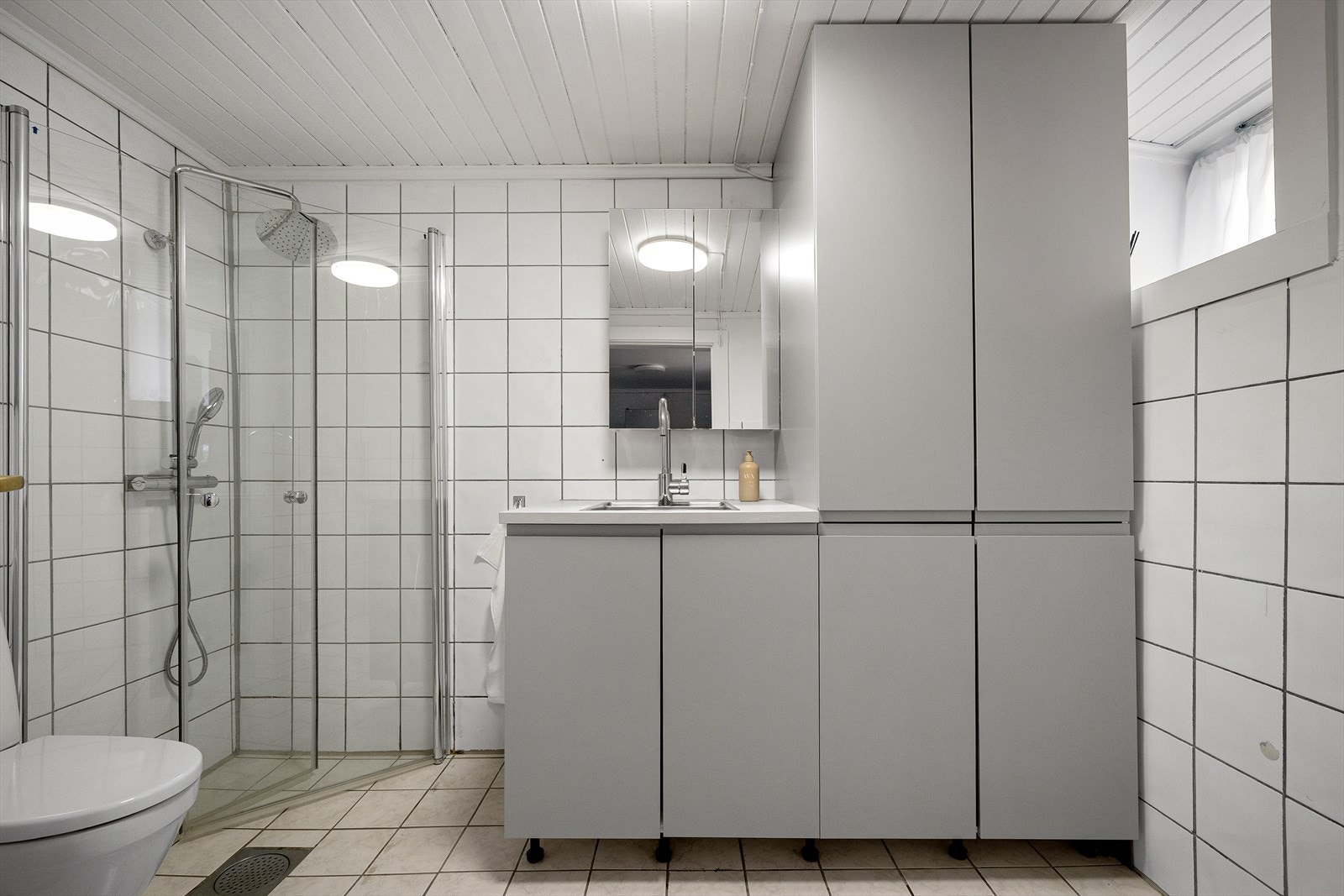 Lyst bad med dusjhjørne og opplegg for vaskemaskin. Galleribilde