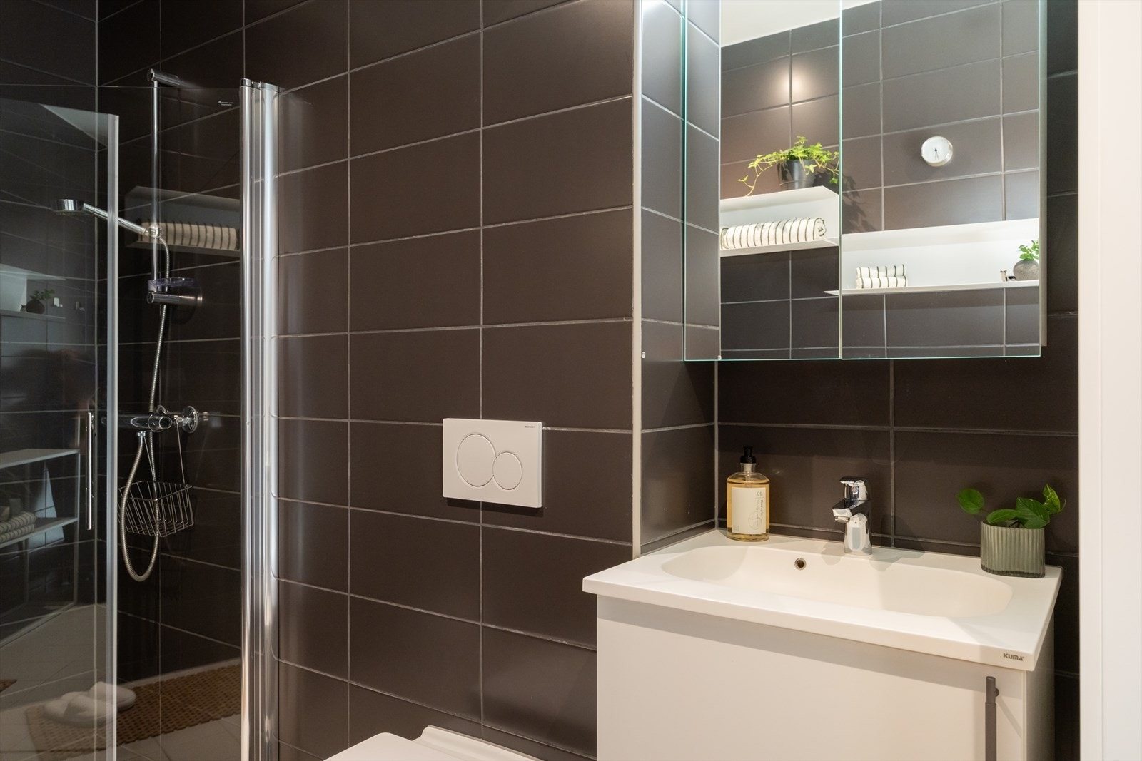 Badet har servantinnredning med skap, speilskap, vegghengt toalett, opplegg og plass til vaskemaskin samt nedsenket dusj med glassdører. Galleribilde