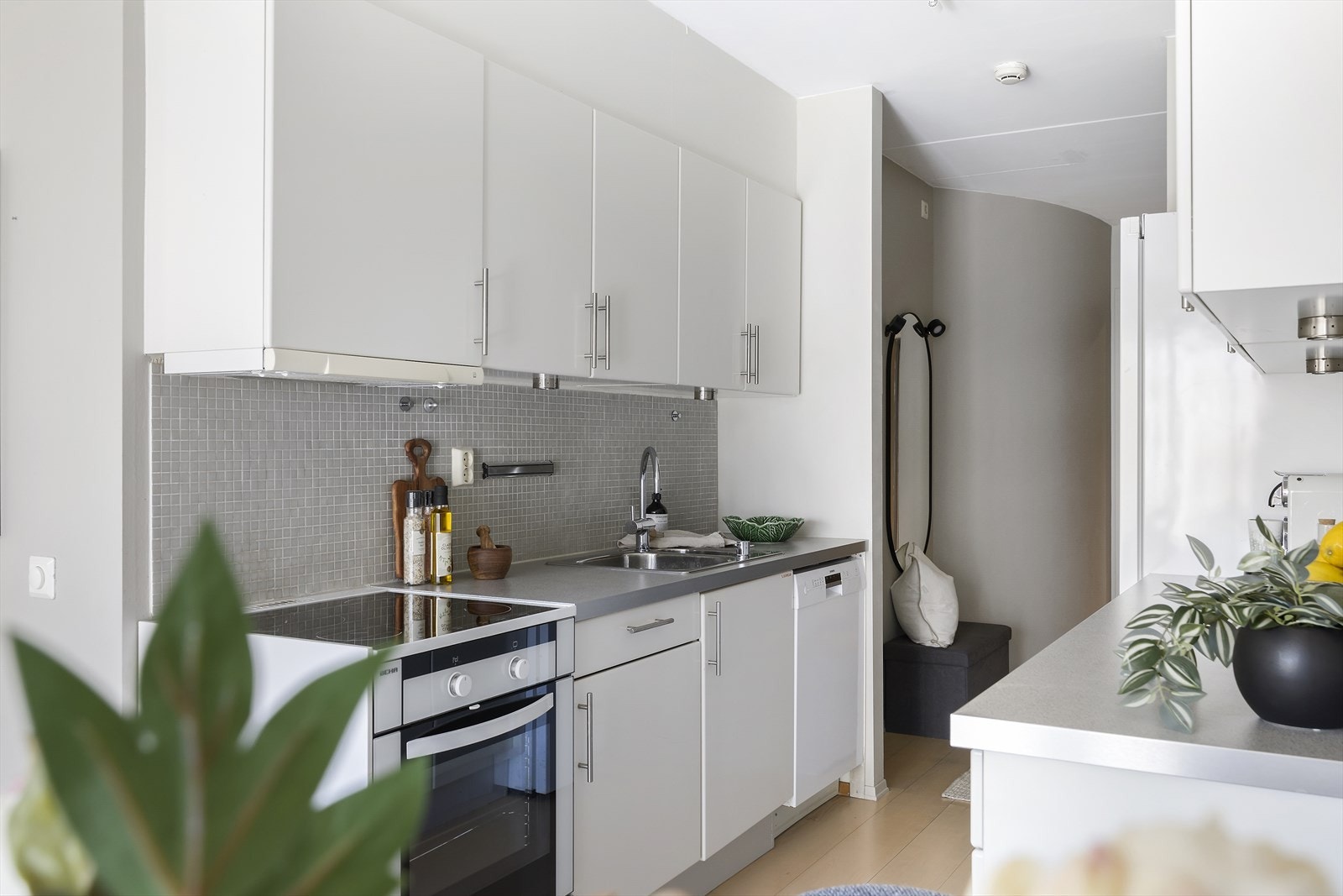 Innredningen har stilrene, glatte fronter som gir et moderne uttrykk, kombinert med laminat benkeplate og nedfelt oppvaskkum i rustfritt stål. Hvitevarer medfølger. Galleribilde