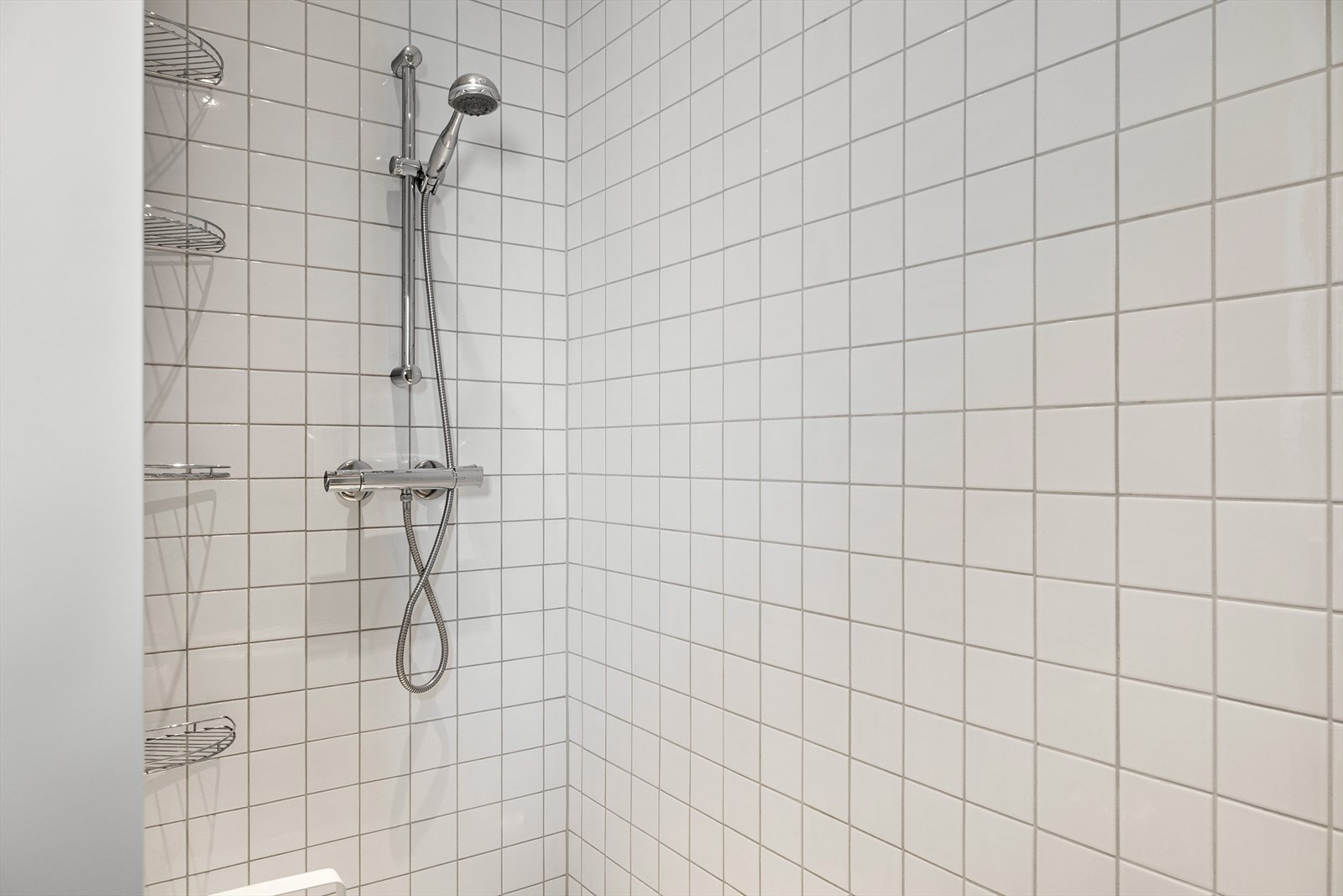 Badet er innredet med 2 nedfelte servanter, veggmontert toalett og dusjvegger/hjørne. Galleribilde