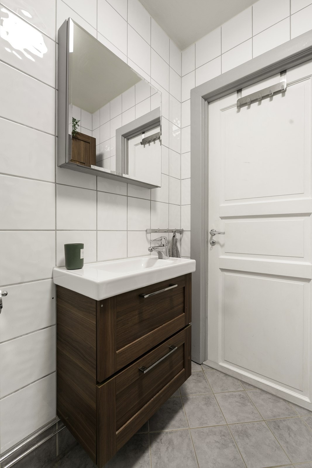 Badet er utstyrt med veggmonterte dusjdører, servant med underskap, speilskap, wc og opplegg for vaskemaskin. Galleribilde