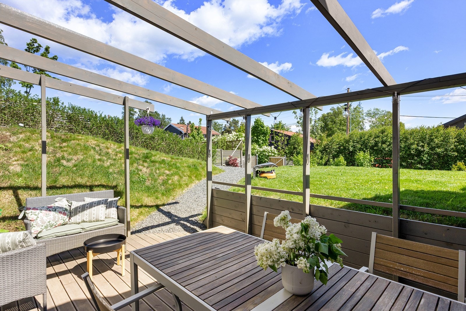 Uteområdet er omkranset av en støttemur i tre mot beplantning og en natursteinsmur ved nedgangen til underetasjen. Galleribilde
