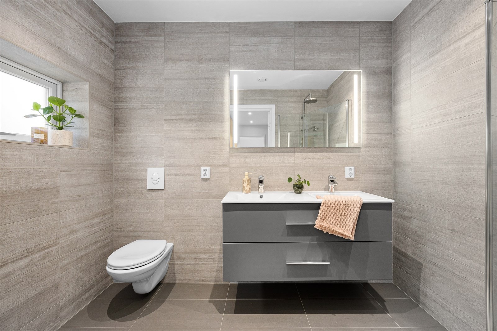 Det lekre badet har dobbelt servant, store fliser, gulvvarme og innfelte downlights i himlingen. Alle boligens bad har fliser med varmekabler i gulv. Galleribilde