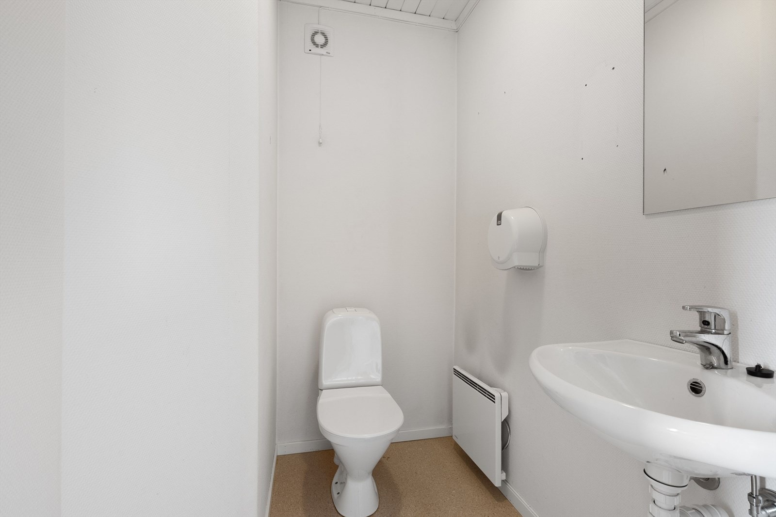 Toalettrom inrnedet med gulvstående toalett, vask og panelovn. Galleribilde