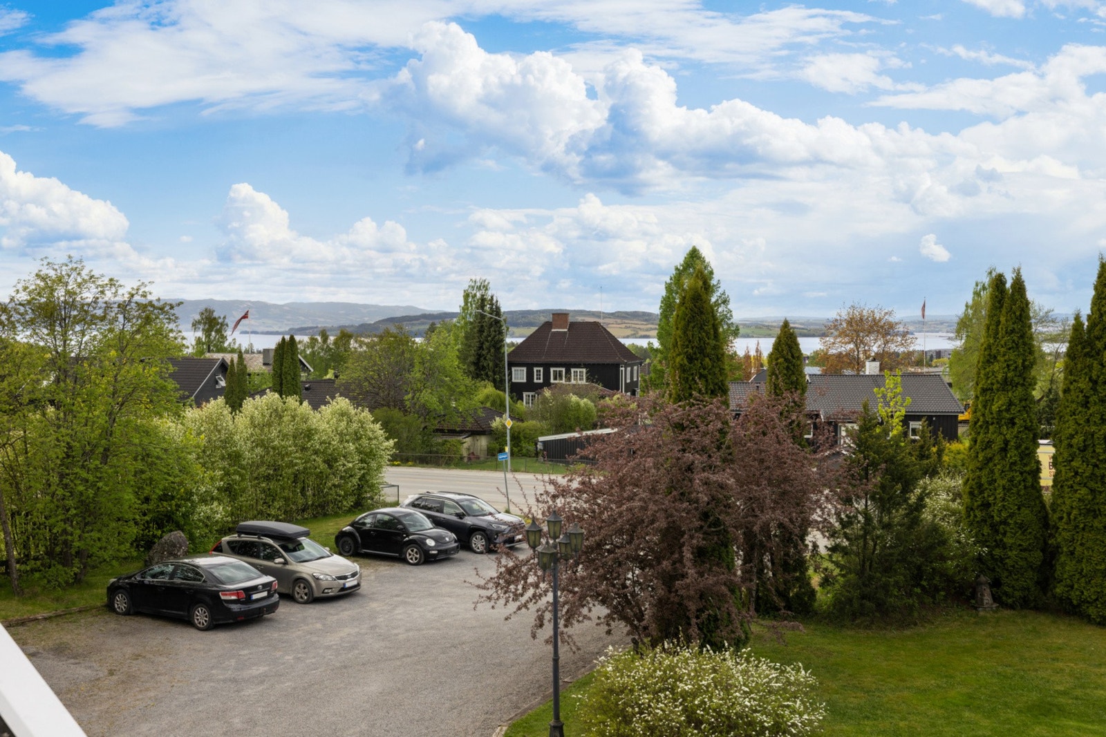 Utsikt fra balkongen mot en frodig hage, og med belysning og flott plen for alle. Galleribilde