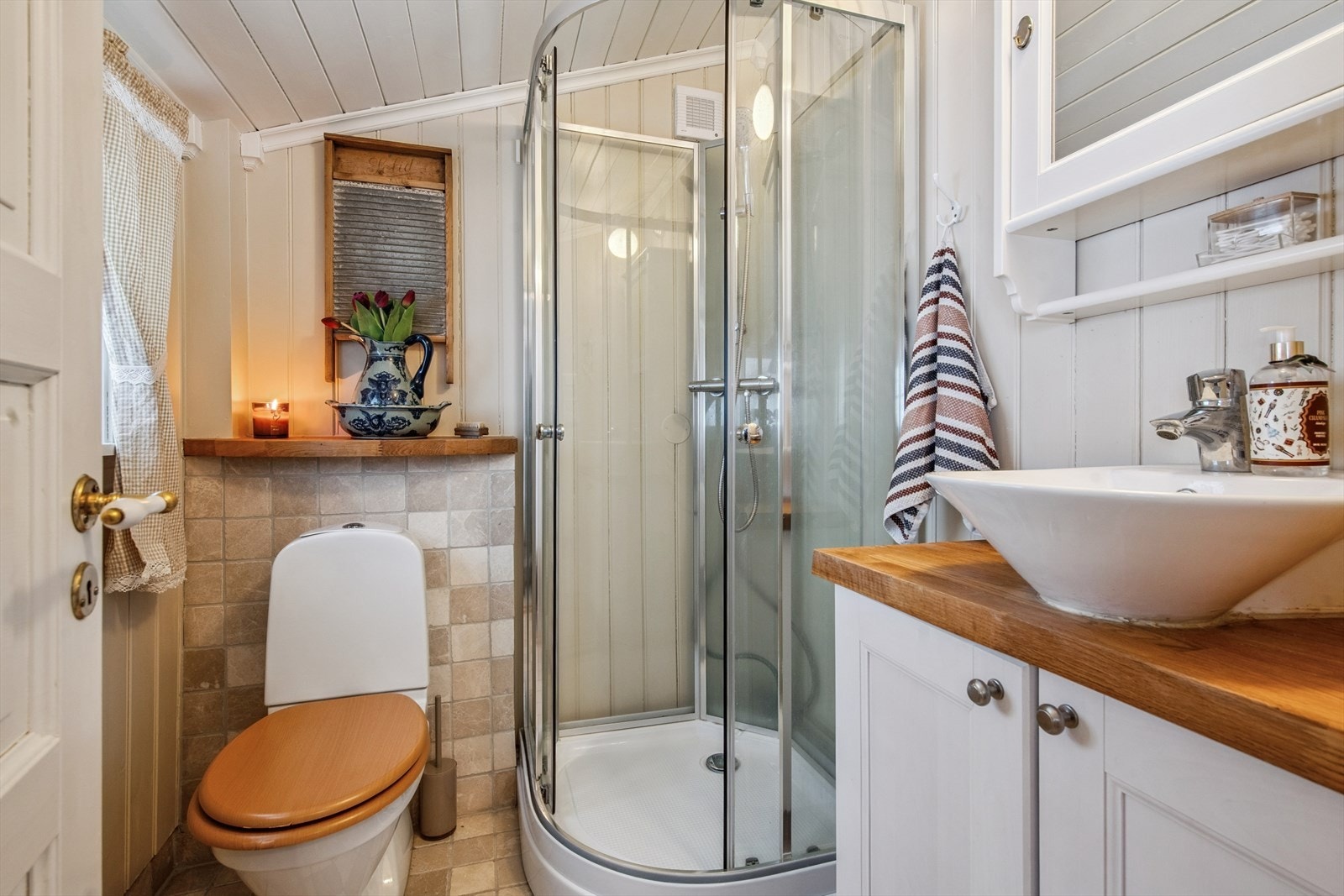 Badet er utstyrt med toalett, servant med underskap og et praktisk dusjkabinett. Galleribilde