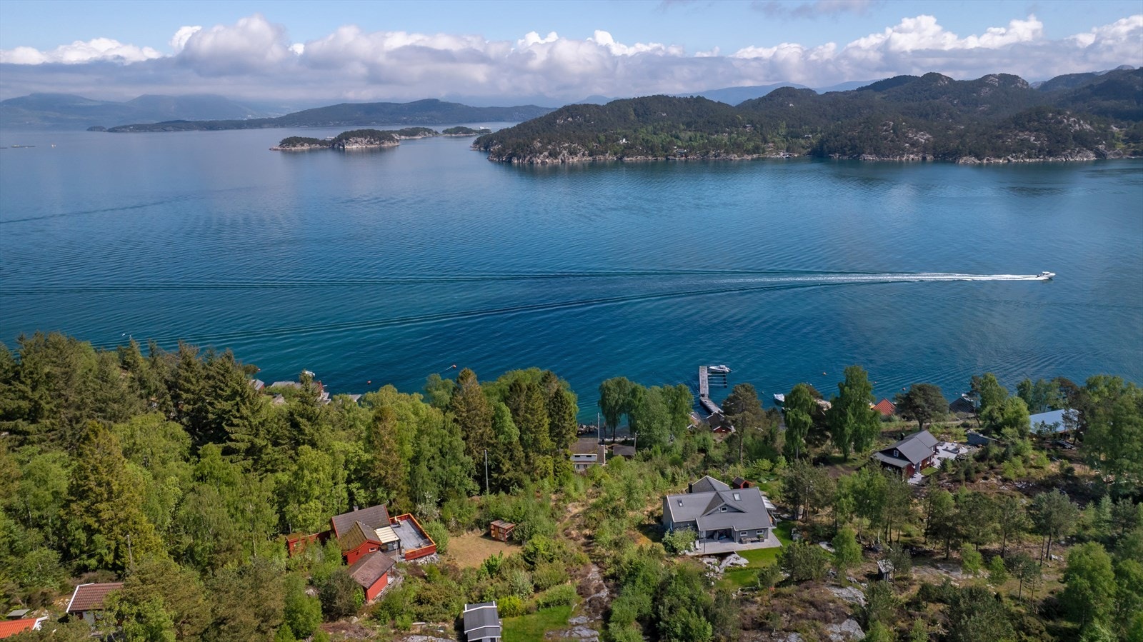 Fritidsboligen fra 1950 ligger plassert i et hyttefelt nær sjøen, og stuen gir direkte utsikt over fjorden gjennom stuevinduet. Galleribilde