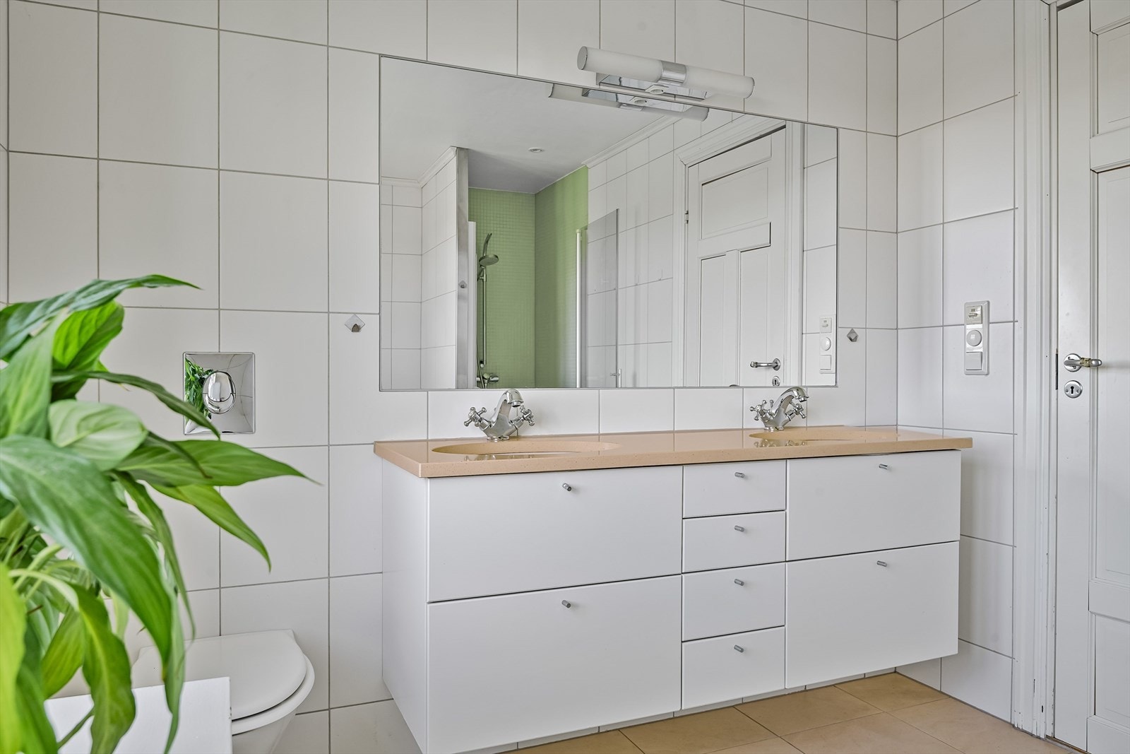 Badet har innredning med to nedfelte servanter og innfliset speil og veggmontert toalett. Galleribilde