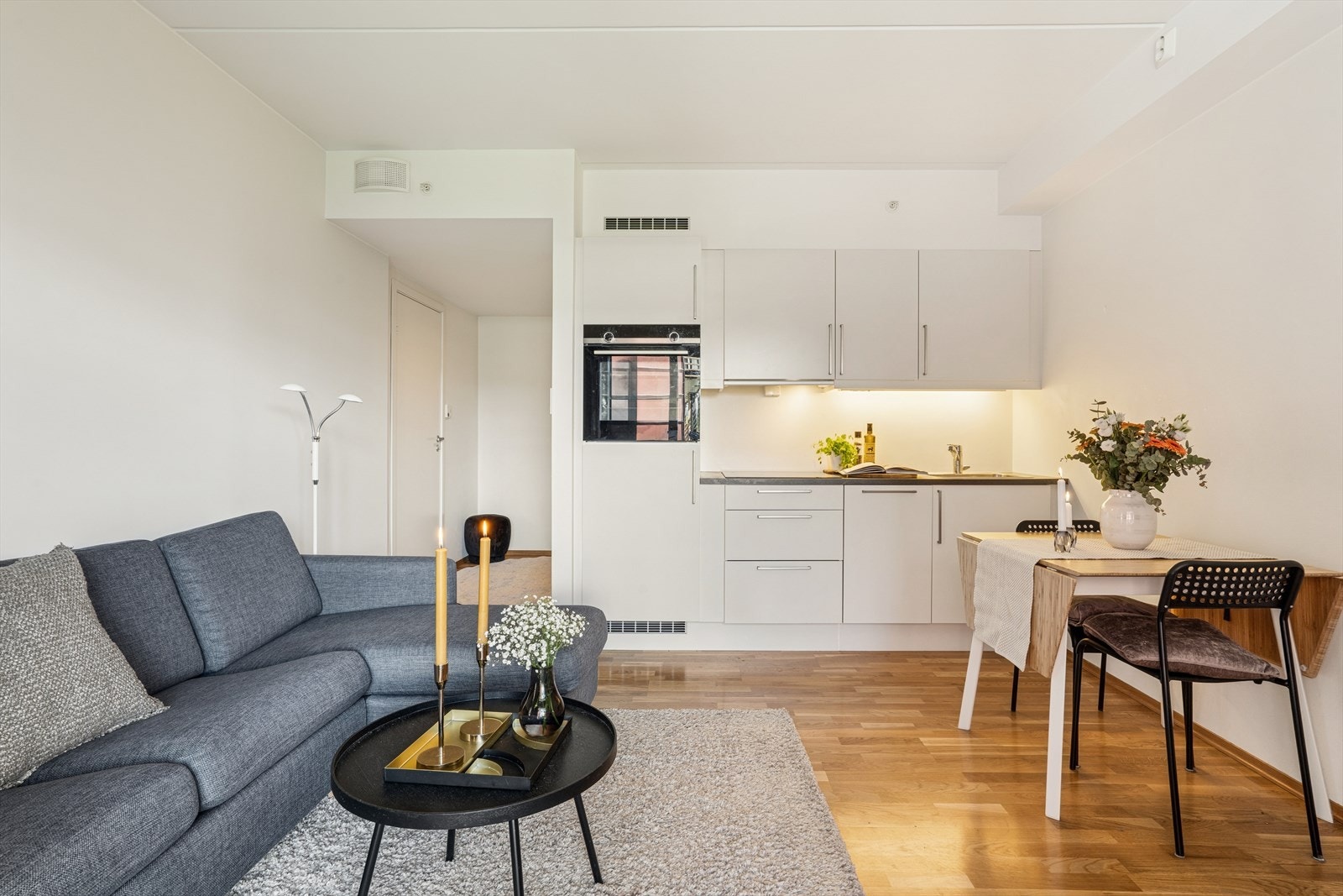 Åpen stue- og kjøkkenløsning med gjennomgående parkett og malte, slette vegger. Galleribilde