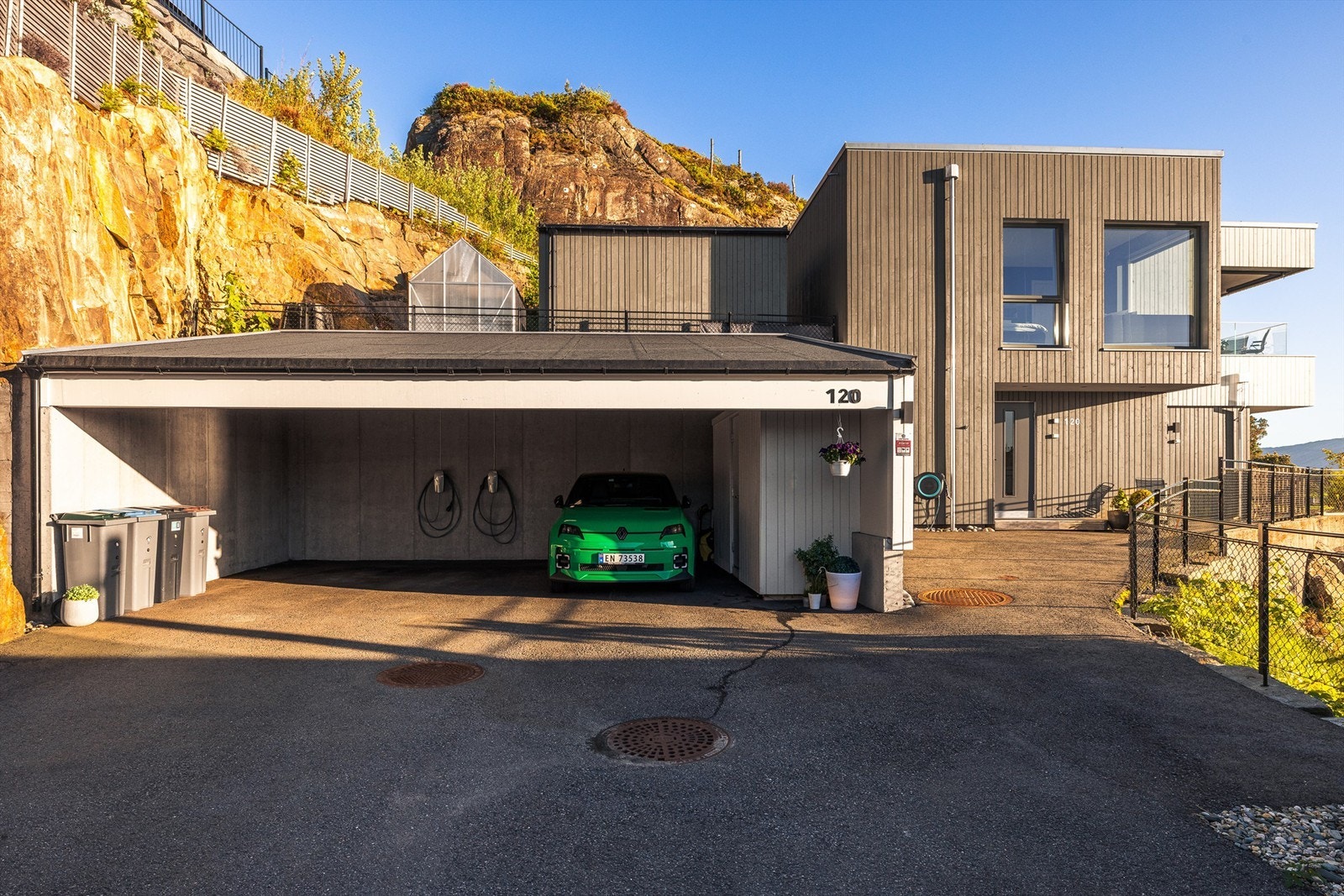 Her kjører du til endes og parkerer i carporten. To elbil ladere medfølger. Carporten hadde opprinnelig plass til tre biler, men etter innvendig bod ble bygget er det plass til 2,5 biler. Galleribilde