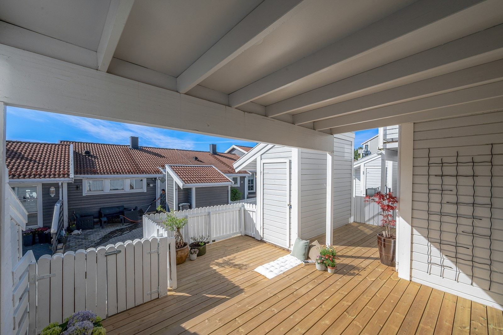 Romslig terrasseplatting foran inngangspartiet utstyrt med terrassebord og rekkverk i malt treverk. Galleribilde