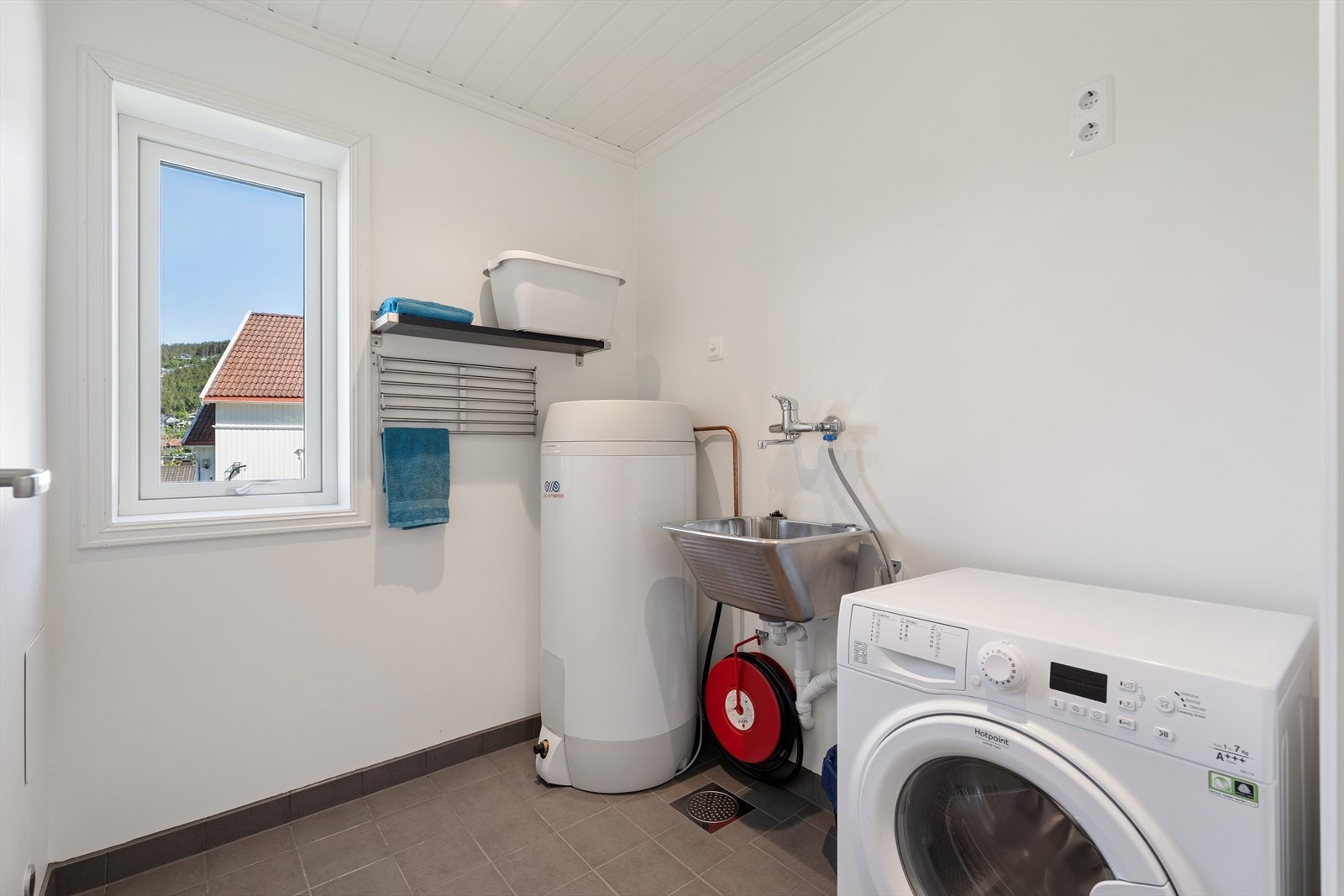 Separat vaskerom med flislagt gulv med varmekabler, opplegg for vaskemaskin og en 200-liters varmtvannsbereder. Galleribilde