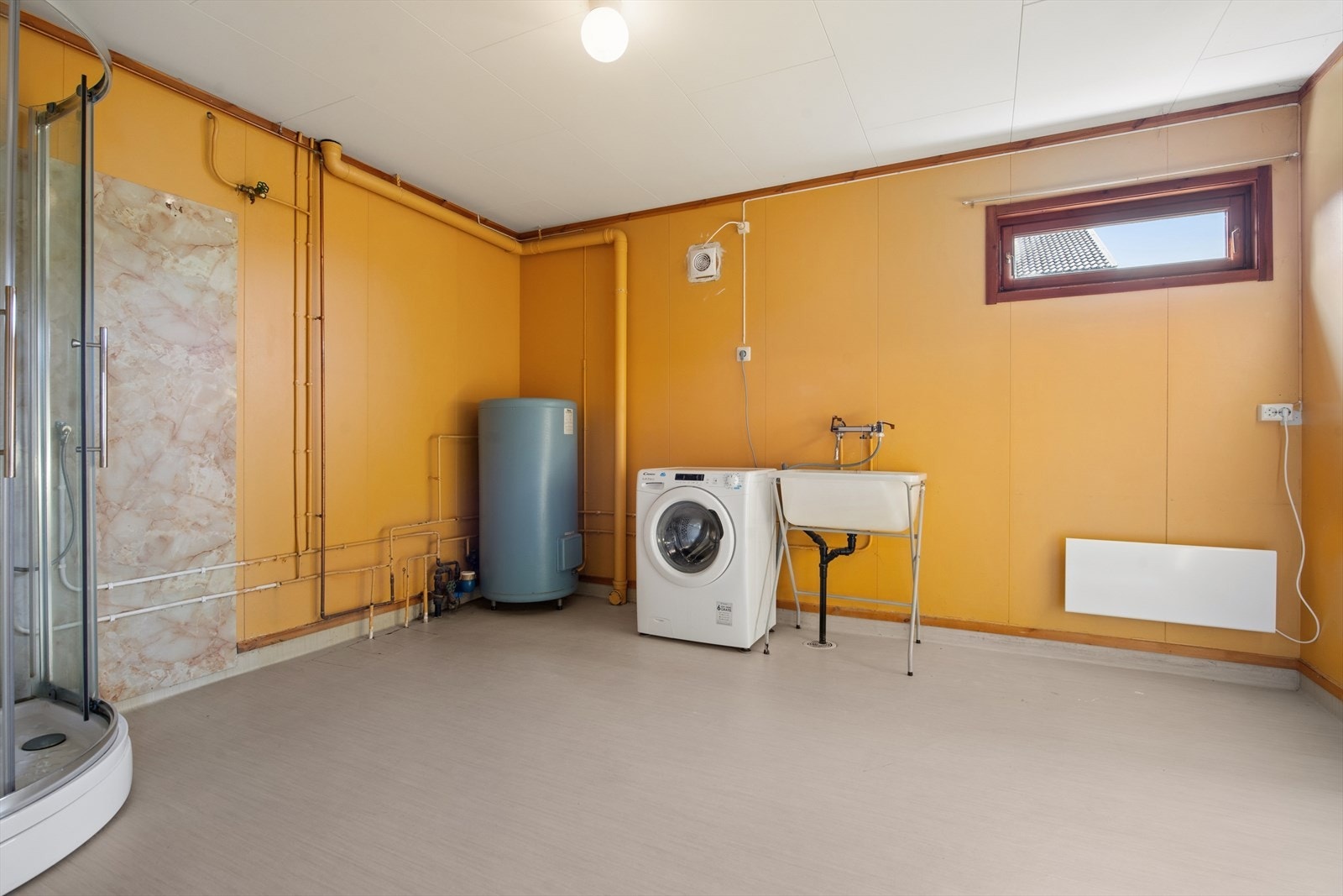 Stort bad/vaskerom med dusjkabinett, opplegg for vaskemaskin og en 200-liters varmtvannsbereder fra byggeåret. Galleribilde