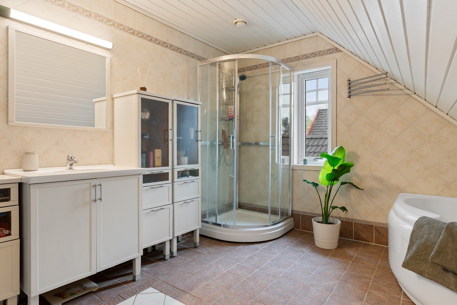 Badet er flislagt og er utstyrt med både dusjkabinett og badekar. Galleribilde