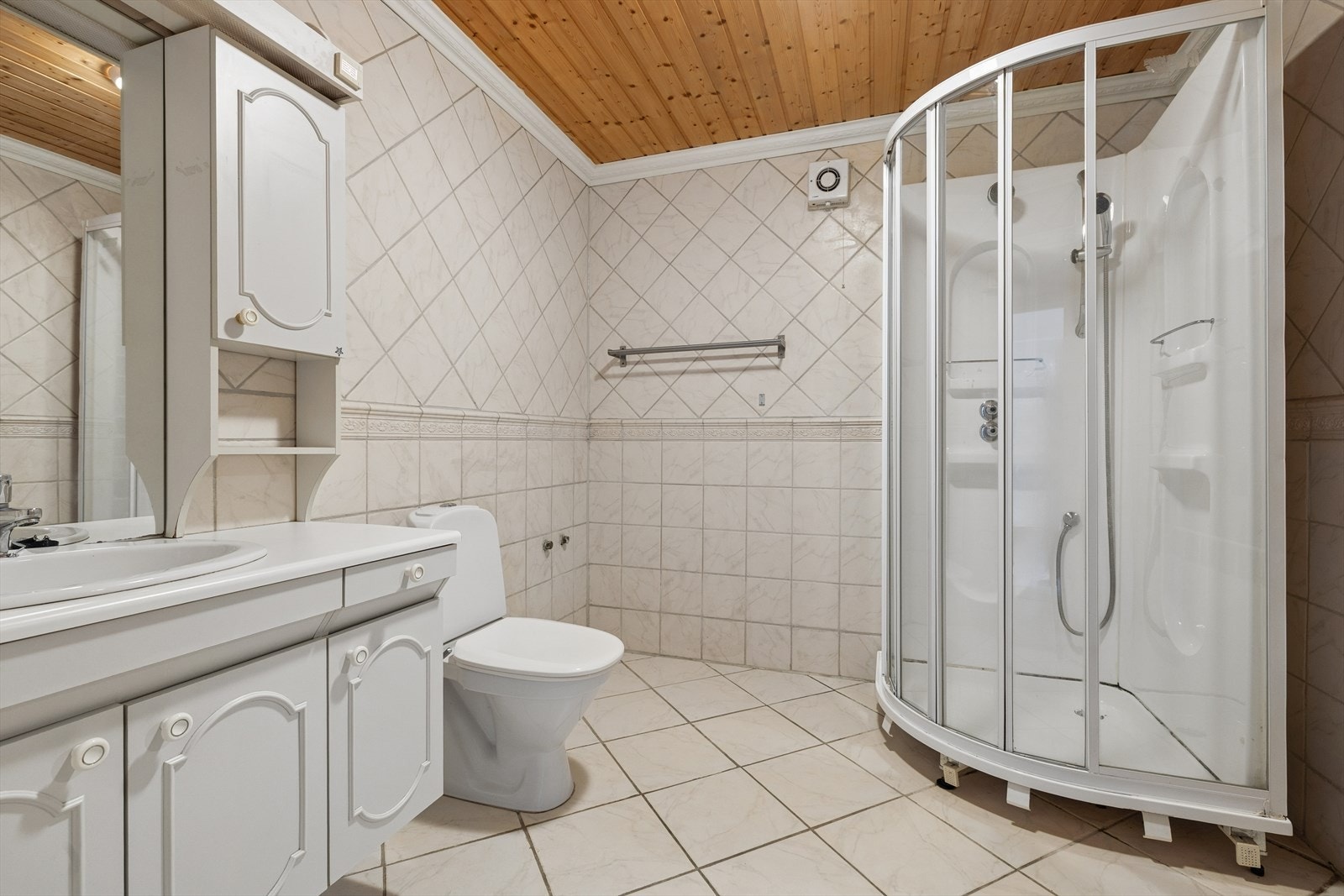 Badet er flislagt m/varmekabler i gulvet. Innredning m/over- og underskap, nedfelt servant i benkeplaten, toalett og dusjkabinett. Galleribilde