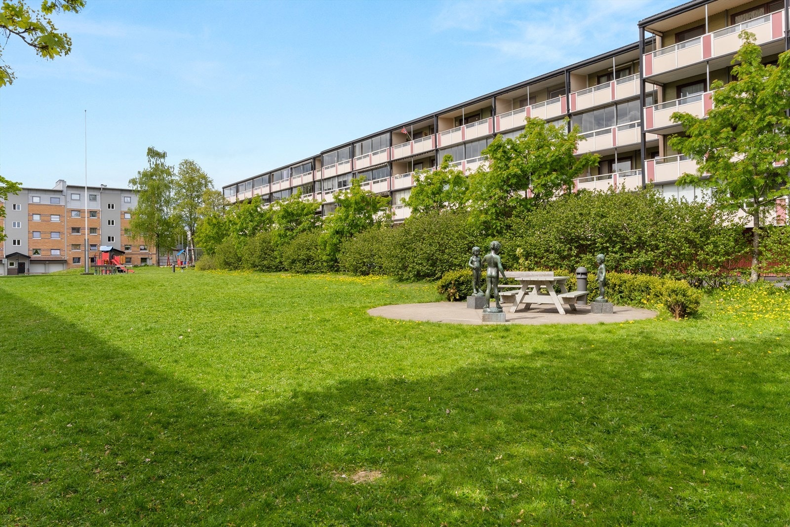 Felles festet tomt opparbeidet med asfalterte adkomstveier/plasser, gressplen, beplantning, trær, lekeapparater, parkeringsarealer m.m. Galleribilde