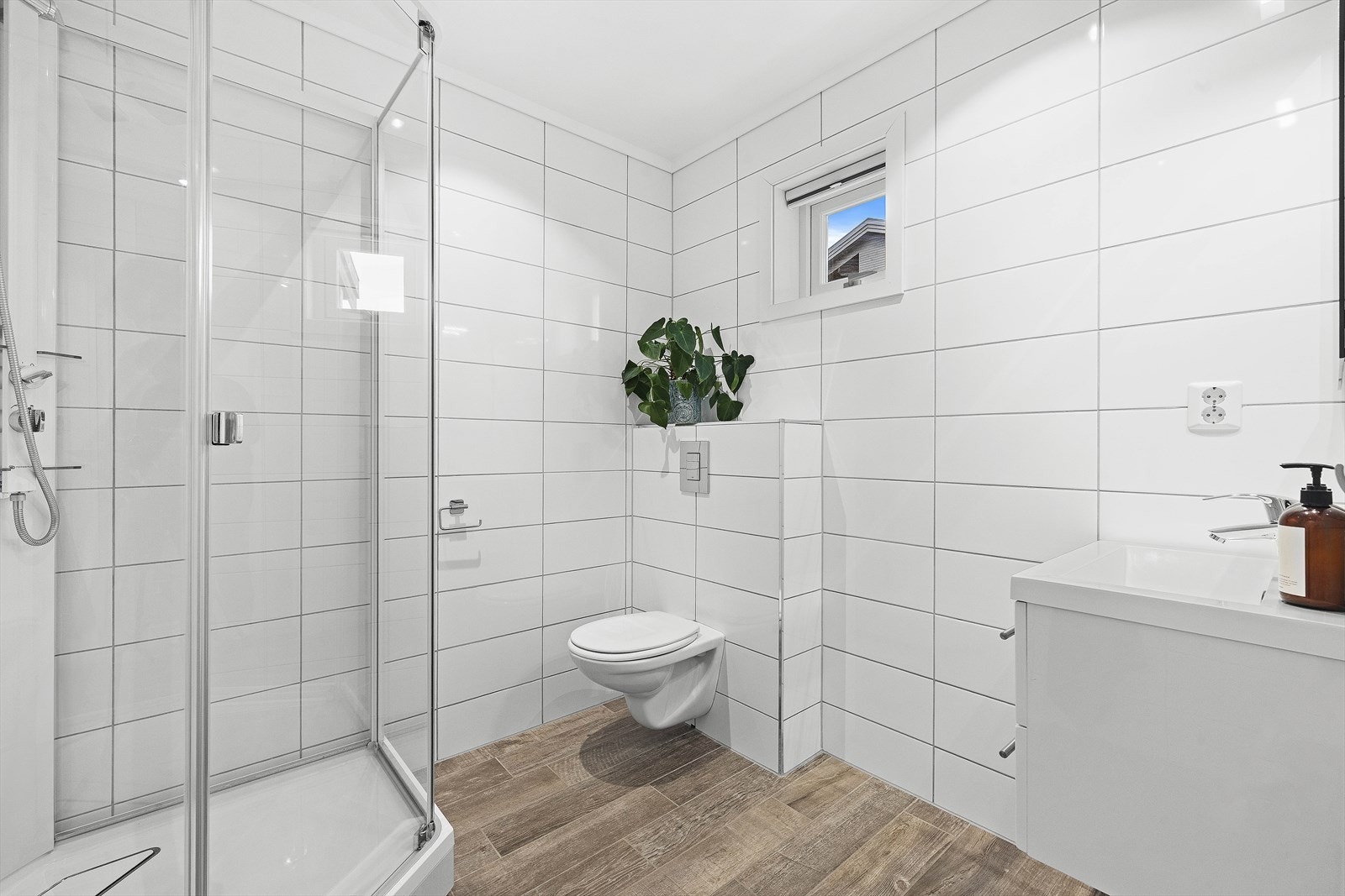 Bad i hovedetasjen har lyse fliser på vegger og gulv, med varmekabler Galleribilde