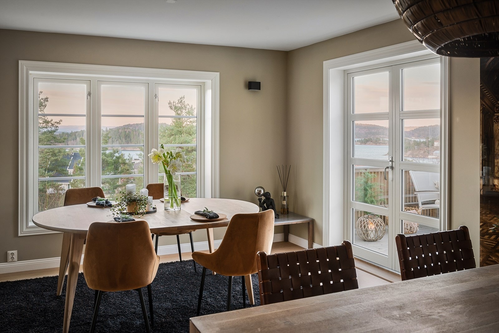 Ved spiseplassen er det et stort vindu med nydelig fjordutsikt og i hver ende av rommet er det tofløyede dører med utgang til veranda og terrasse - perfekt om man vil ta med måltidene ut. Galleribilde
