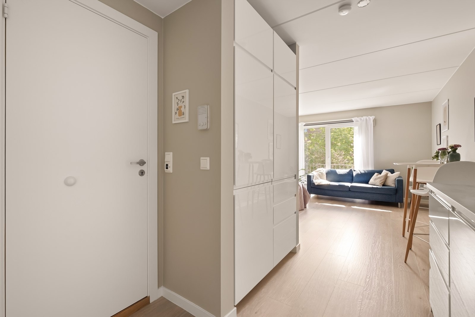 Fra entréen åpner leiligheten seg opp i en lys og sosial sone med kjøkken og stue. Galleribilde