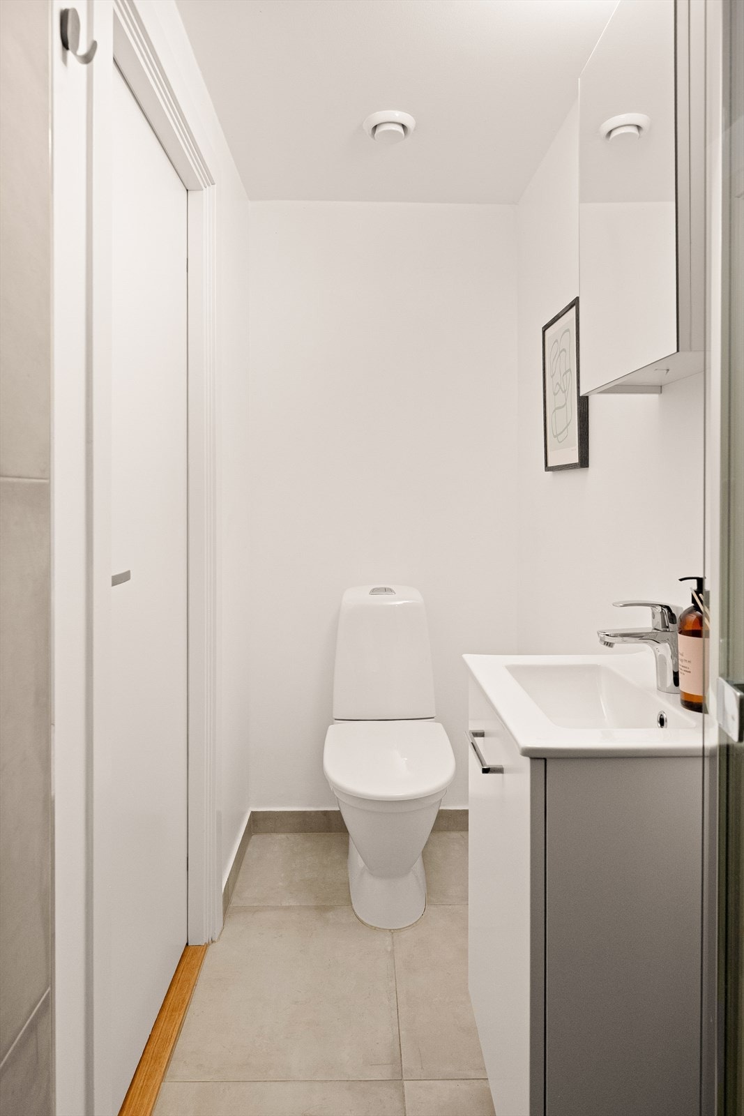 Badet er utstyrt med toalett, innredning med servant, speilskap og dusjdør i glass. Galleribilde