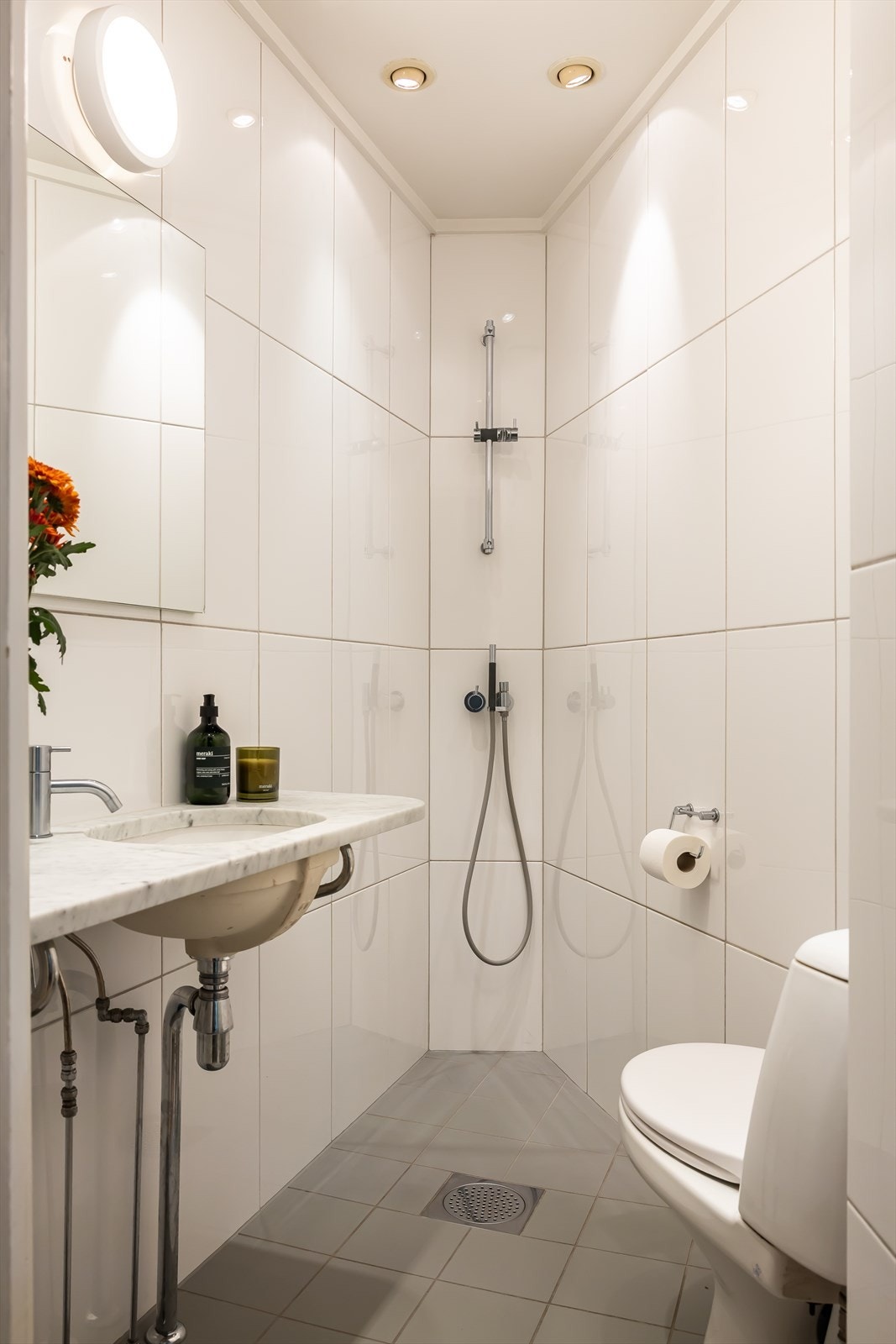 Badet har adkomst fra entreen. Fliser på vegg og gulv, servant med benkeplate i marmor. Det er innfelt skap i veggen bak speil Galleribilde