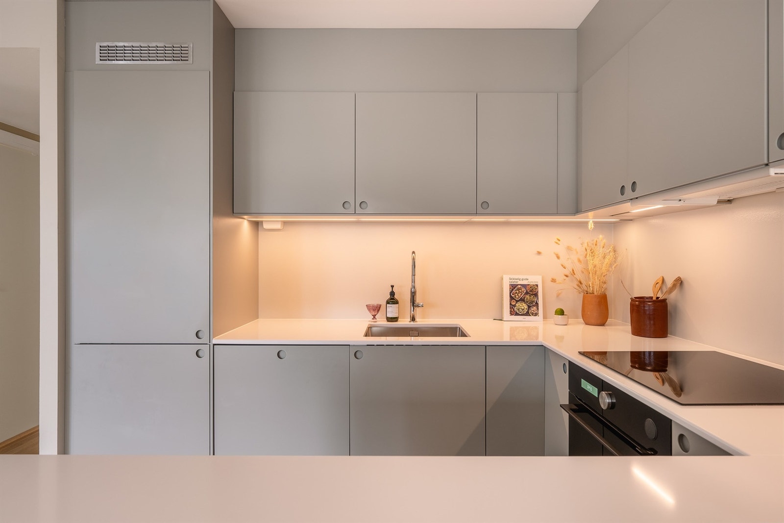 Kjøkkenet ble oppgradert i 2021 med stilren innredning fra IKEA og Noremax, med glatte fronter, kompositt benkeplate og nedfelt vask med moderne armatur. Galleribilde