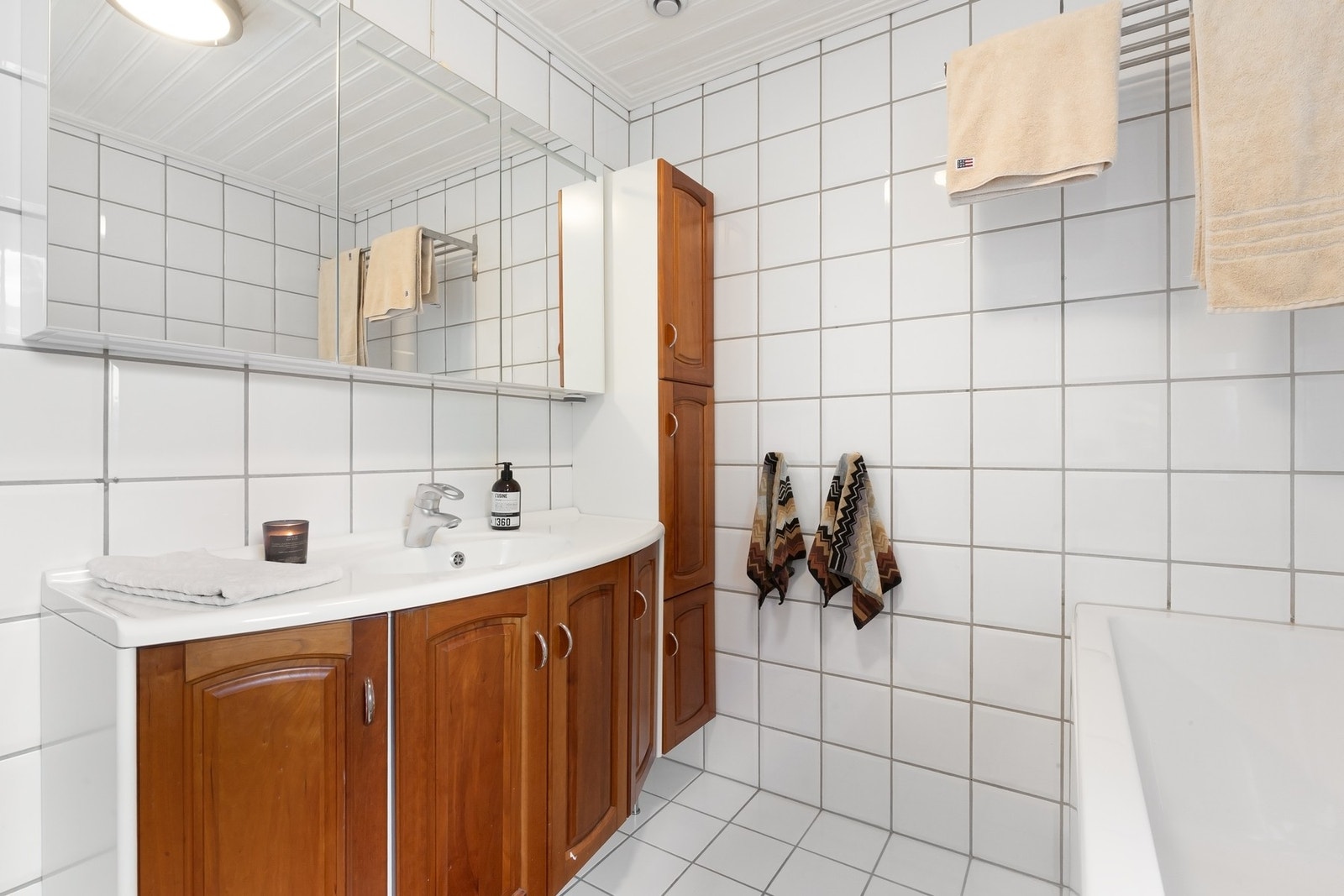 Badet er innredet med servant nedfelt i innredning med god oppbevaringsplass, speil, høyskap, klosett og badekar. Galleribilde
