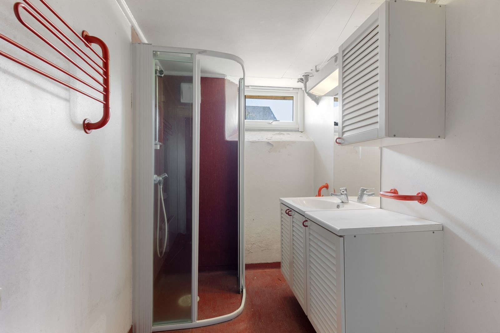 Kjelleren er en råkjeller av eldre standard. Badet er antatt fra 1970/80-tallet med eldre overflater, dusjvegger og veggmontert innredning. Galleribilde