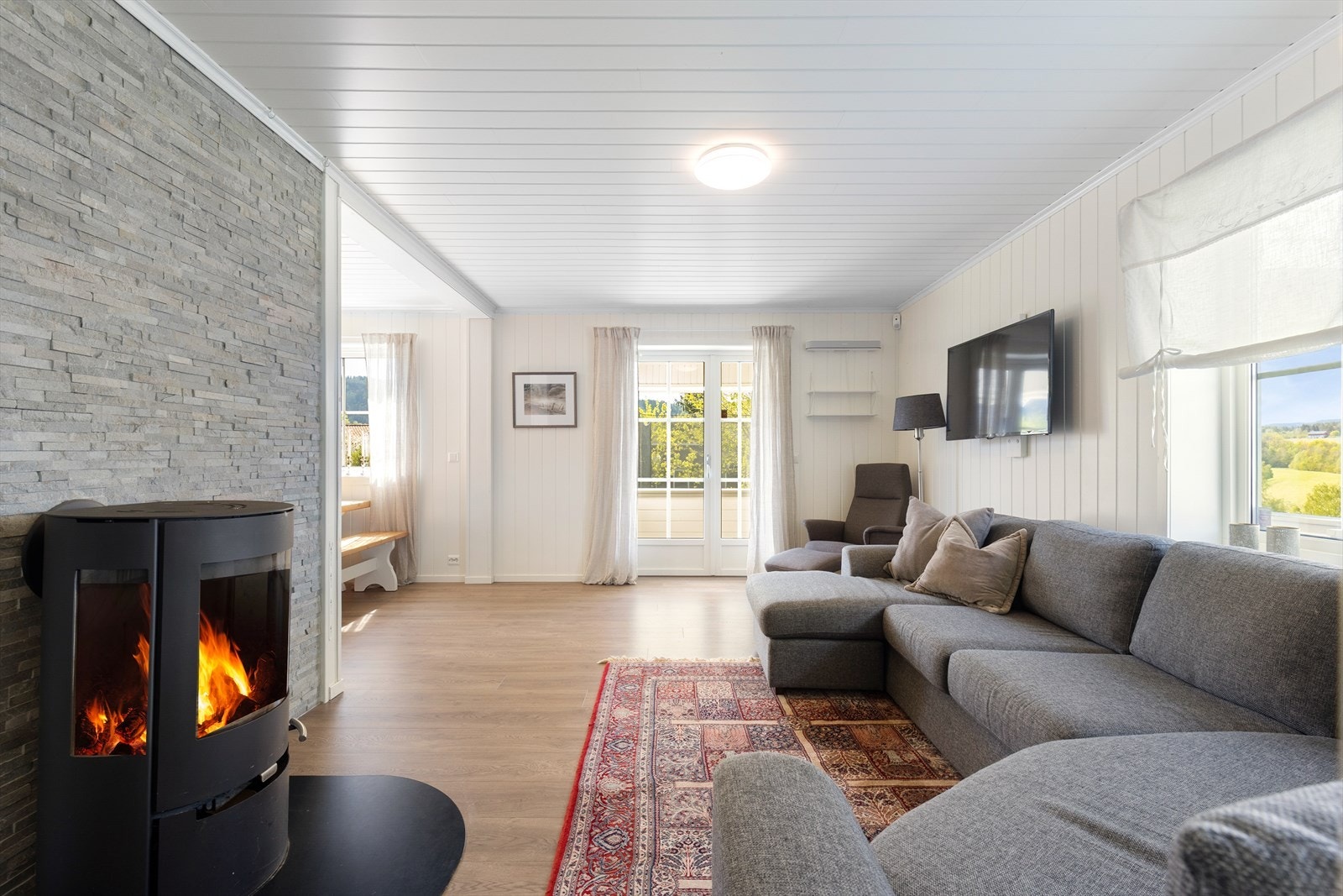 Lys og romslig stue med god plass til en stor sofagruppe og utgang til den takoverbygde verandaen. Verandadør fra 2017. Galleribilde