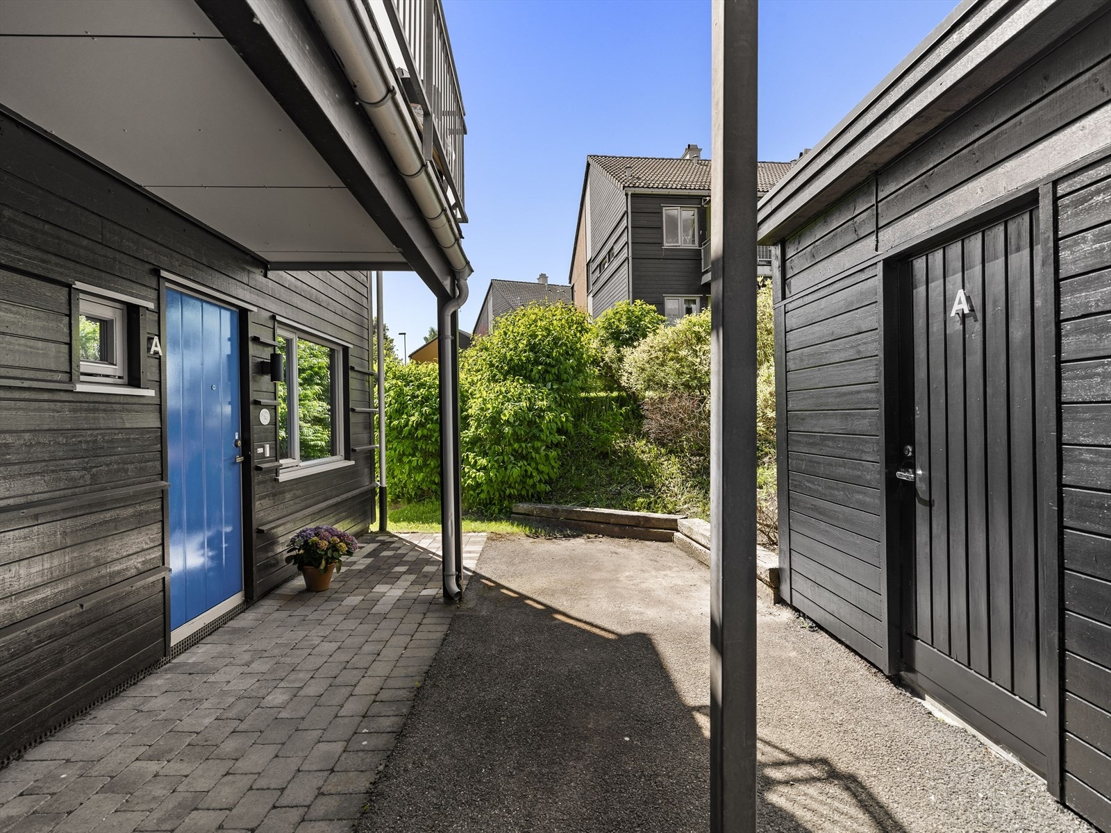 Borettslagets tomt er opparbeidet med beleggningstein og variert beplantning. Galleribilde