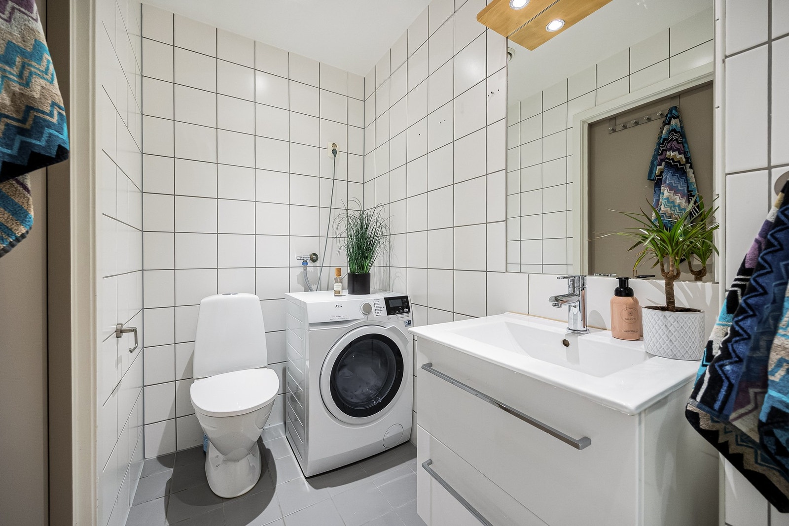 Videre er det veggmontert servantskap med heldekkende vask og ettgreps armatur i krom. Rommet har gulvstående klosett samt opplegg for vaskemaskin. Galleribilde