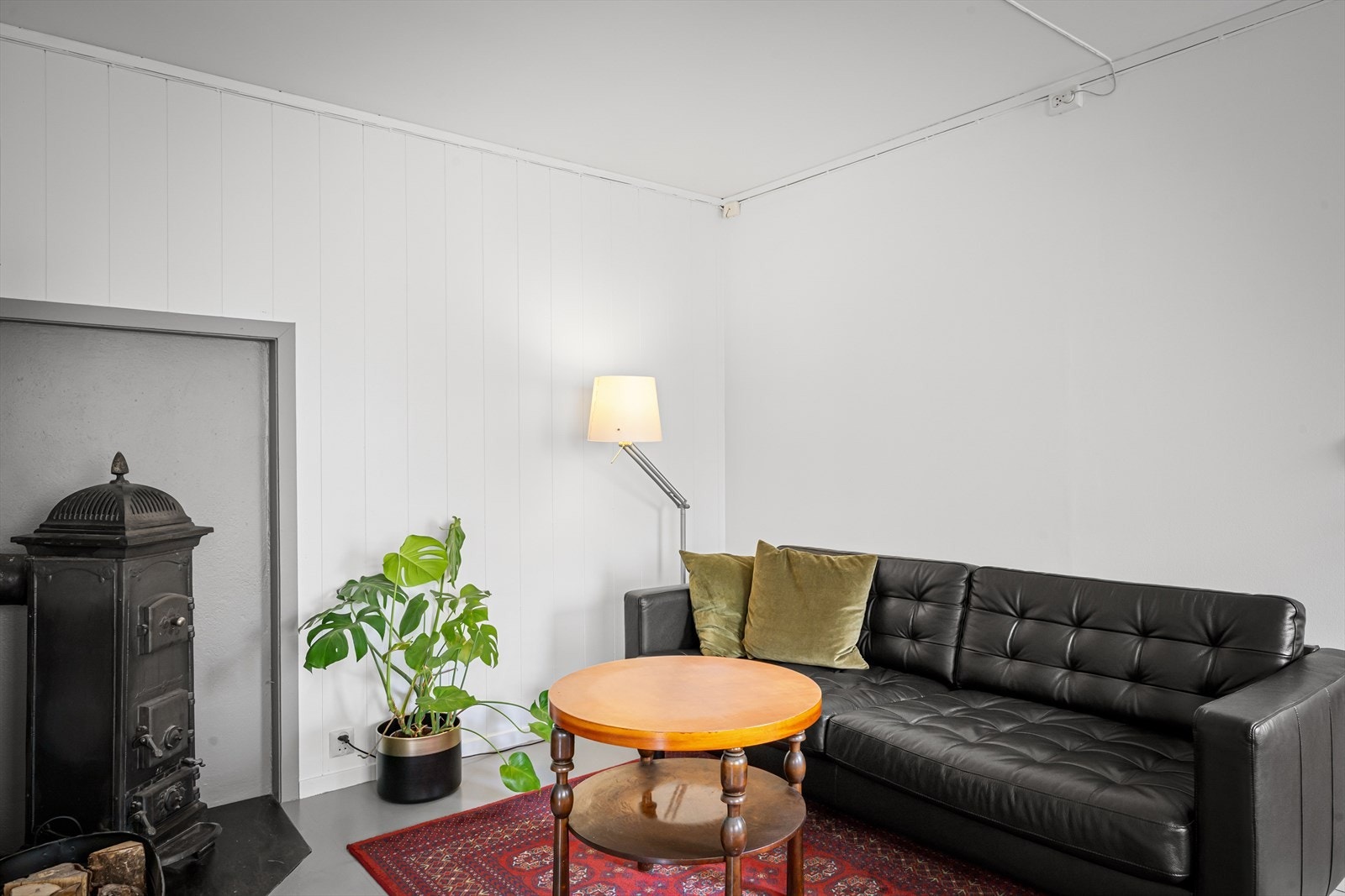 Leiligheten har en åpen løsning mellom stue og kjøkken, med en klassisk vedovn som gir både varme og karakter. Galleribilde
