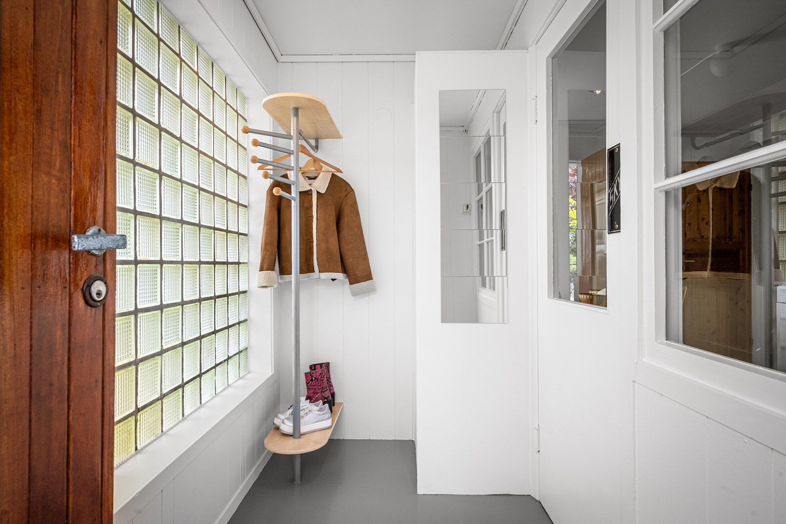 Entréen har malte panelvegger og glassbyggerstein som slipper inn dagslys. Galleribilde