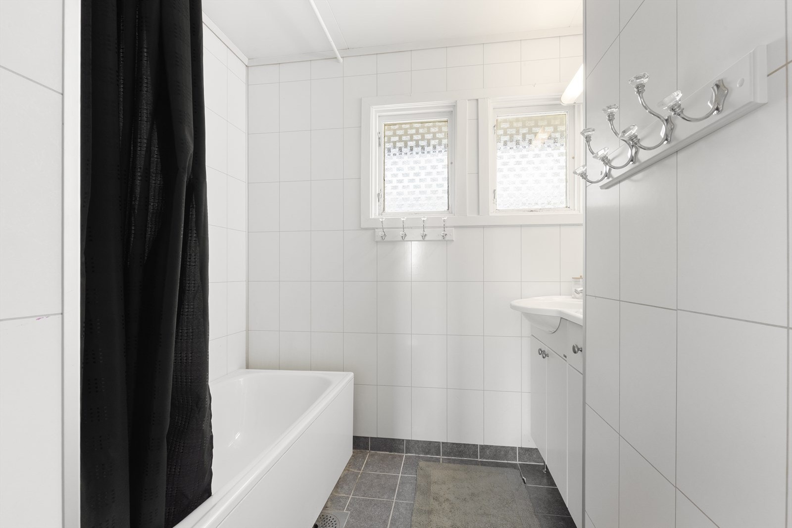 Badet i første etasje har flislagt gulv med elektriske varmekabler, badekar med dusj og servantinnredning. Galleribilde