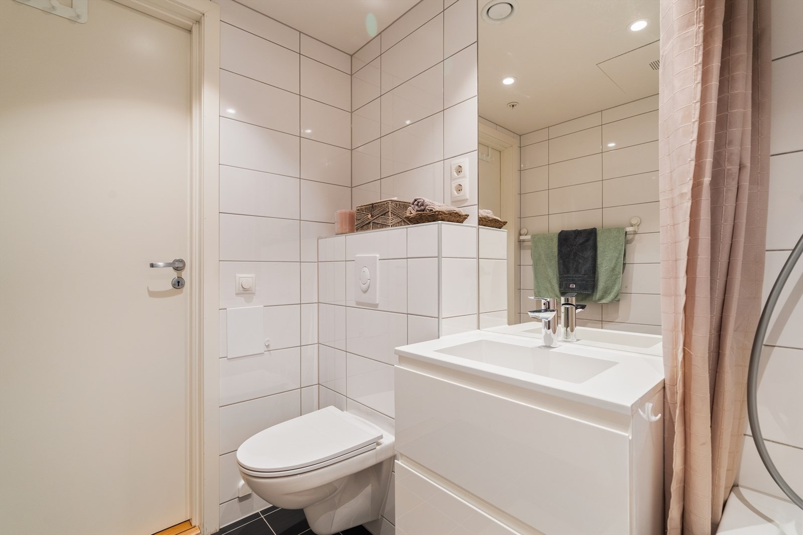 Badet er utstyrt med nedfelt servant, veggmontert toalett og badekar Galleribilde