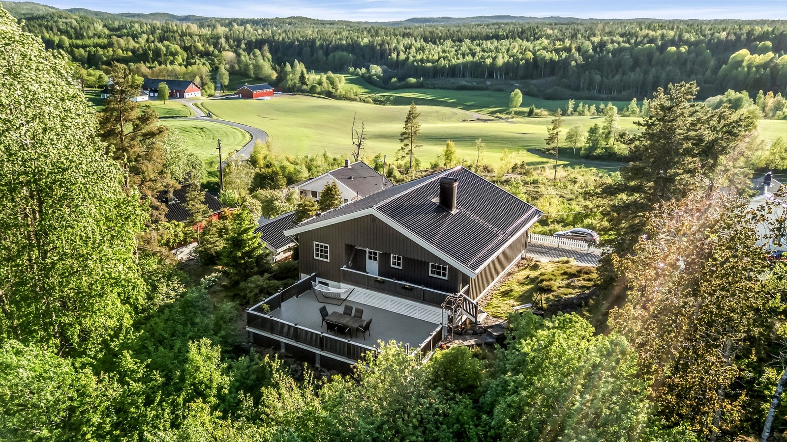 Skjermet og koselig sone på baksiden av huset som er omkranset av skog Galleribilde