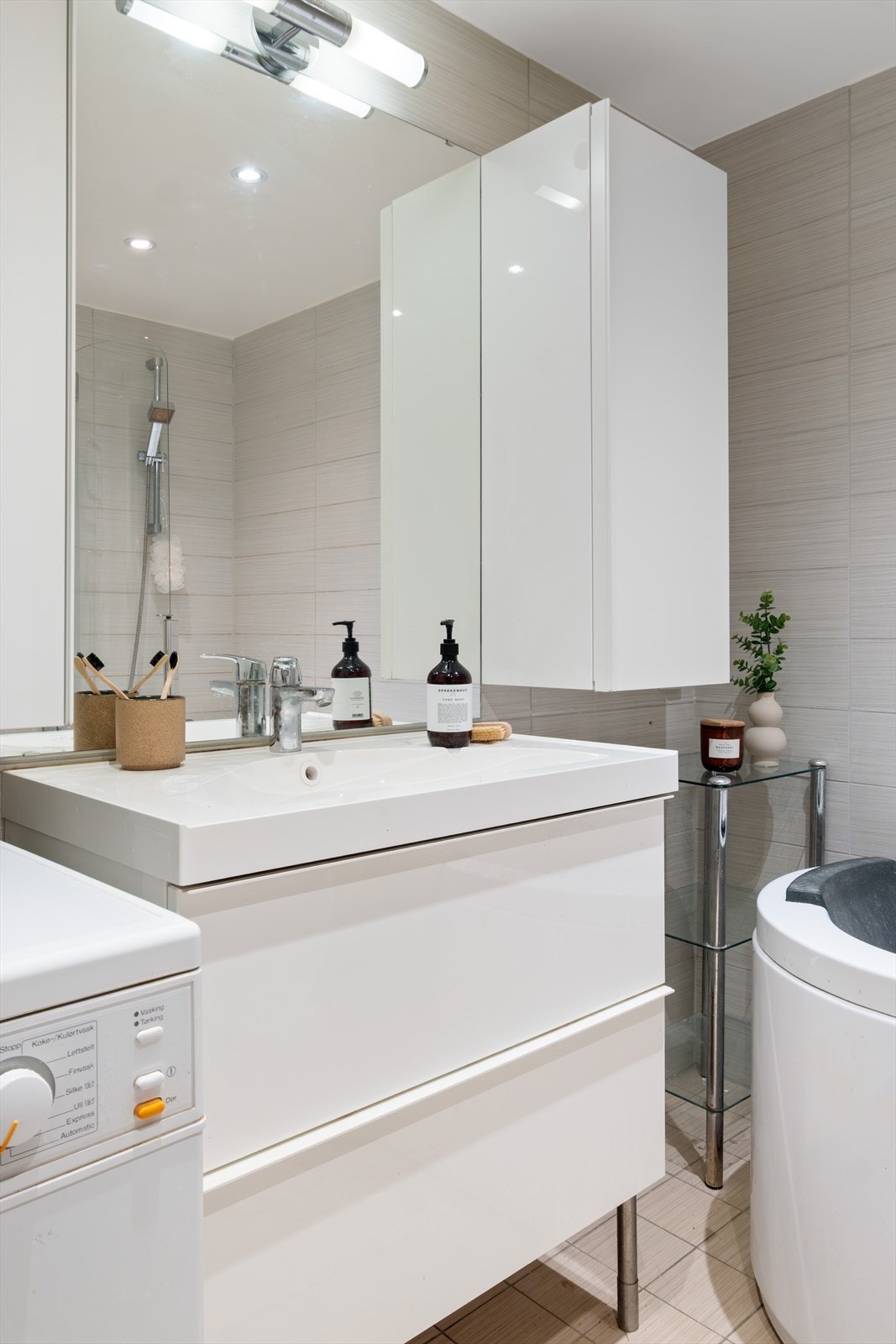 Badet er utstyrt med vegghengt toalett, servantinnredning med servant, ettgreps blandebatteri, blandebatteri/dusjarmatur, og dusjkabinett. Galleribilde