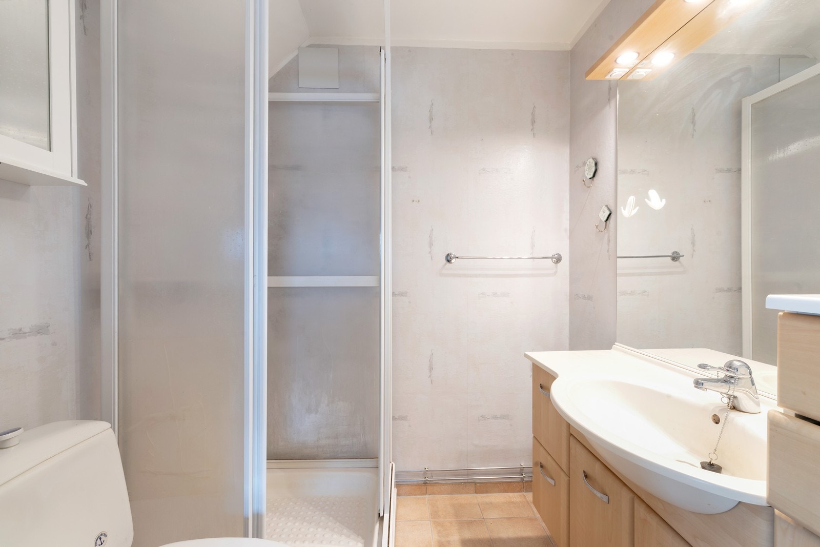 Badet har dusjkabinett, servant med underskuffer, skap og toalett. Galleribilde