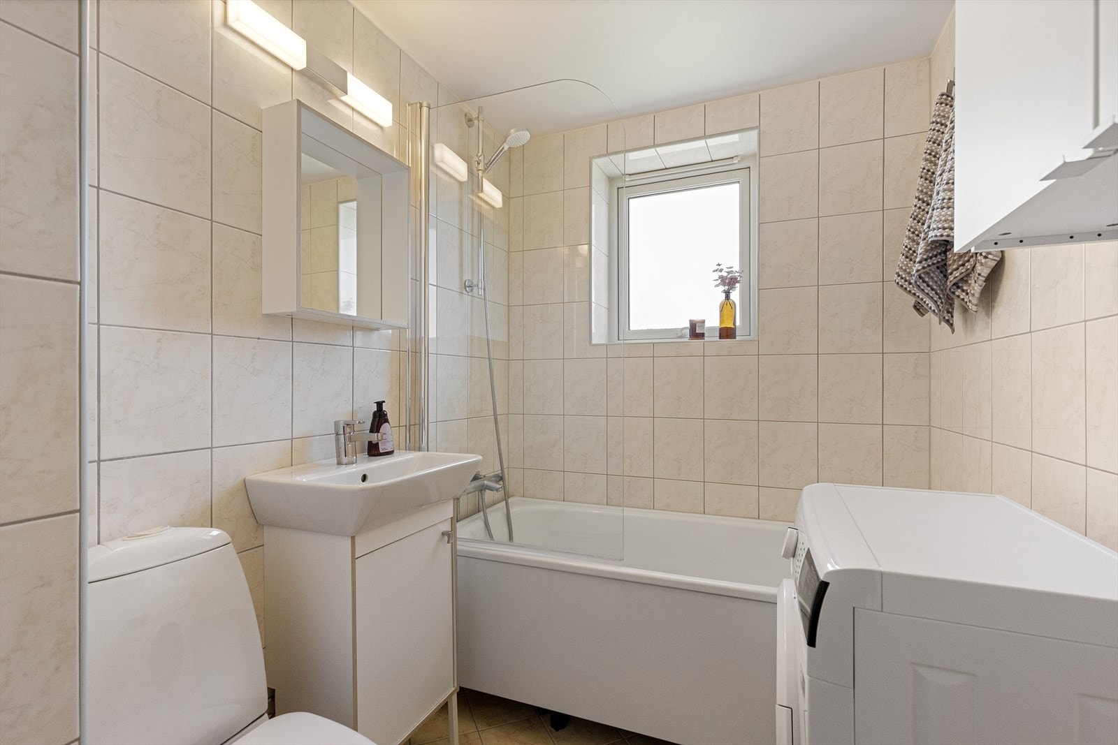 Badet er innredet med badekar, servant med oppbevaringsmuligheter og opplegg for vaskemaskin. Det er også varmekabler i gulv. Galleribilde