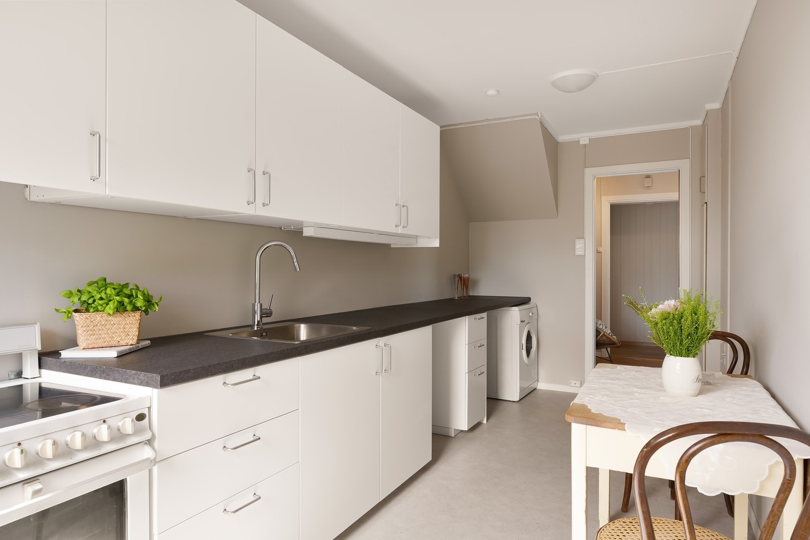 Lyst og delikat kjøkken med plass til et hyggelig frokostbord. Det er plass til frittstående hvitevarer, og det er opplegg for vaskemaskin. Galleribilde