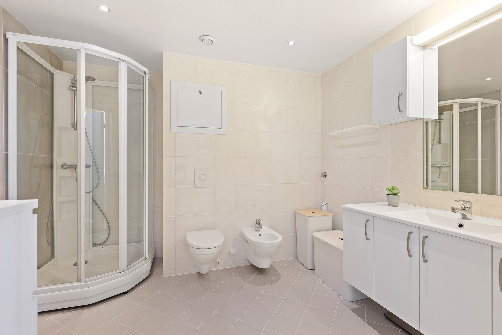 Badet har lys innredning med nedfelt servant og skap under, overskap og speil med lys over, dusjkabinett, vegghengt toalett og bide`. Varme i gulv gir en lun og fin start på dagen. Galleribilde