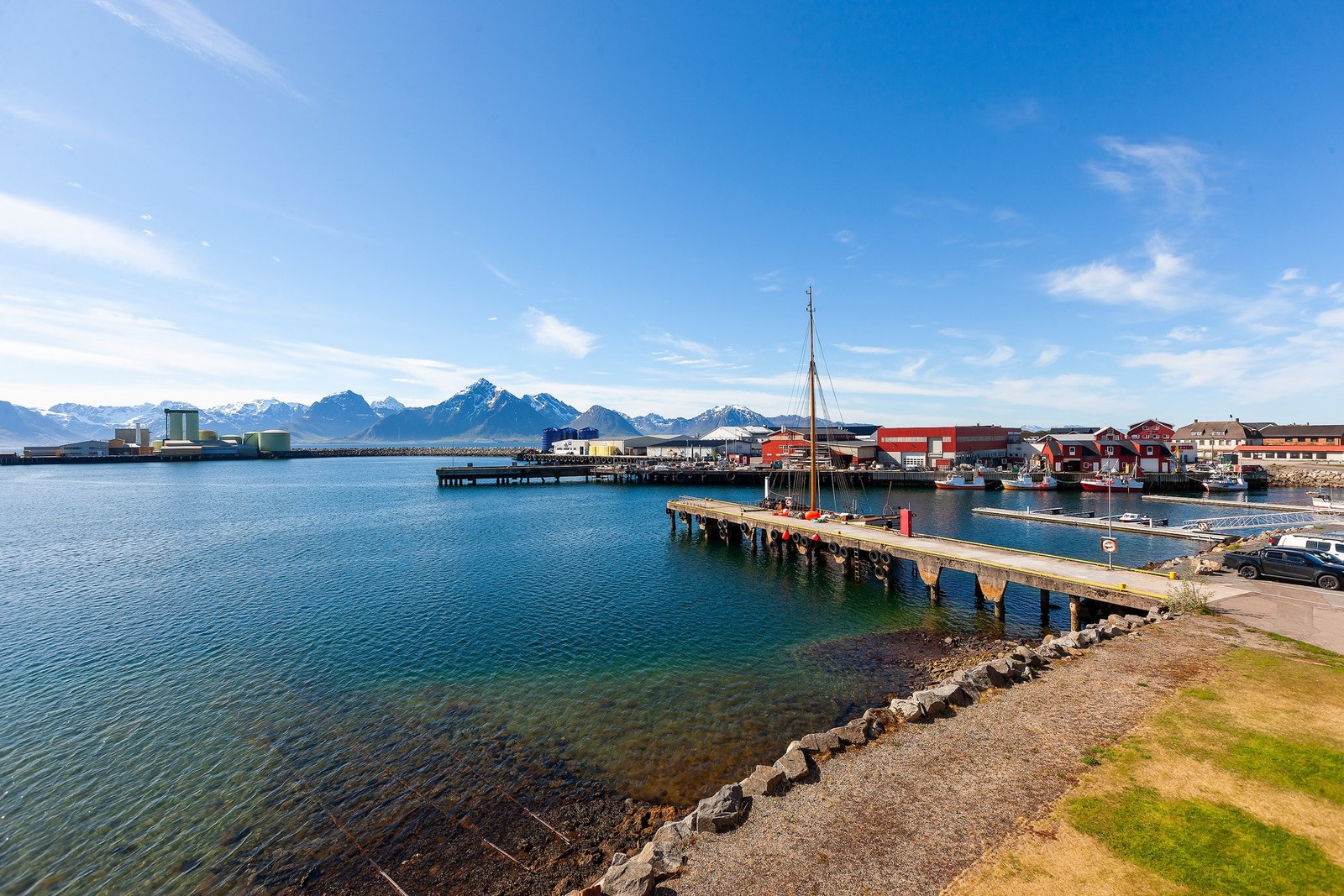 Bilde viser nærområdet med sjø, brygge og fjell i bakgrunnen. Galleribilde