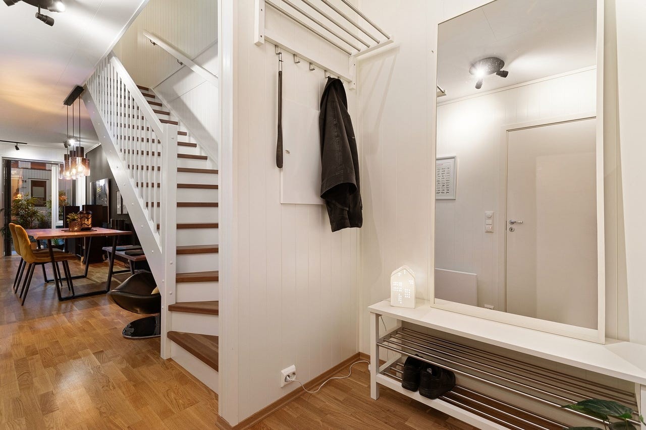 Innbydende entré med parkett på gulvet og trapp som leder til andre etasje. Galleribilde